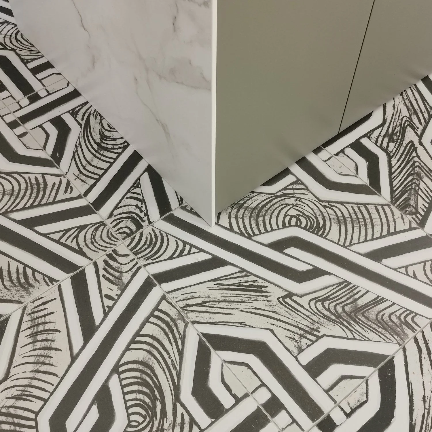 Carrelage noir et blanc avec motifs géométriques, nettoyage ou usure visible sur certains carreaux.