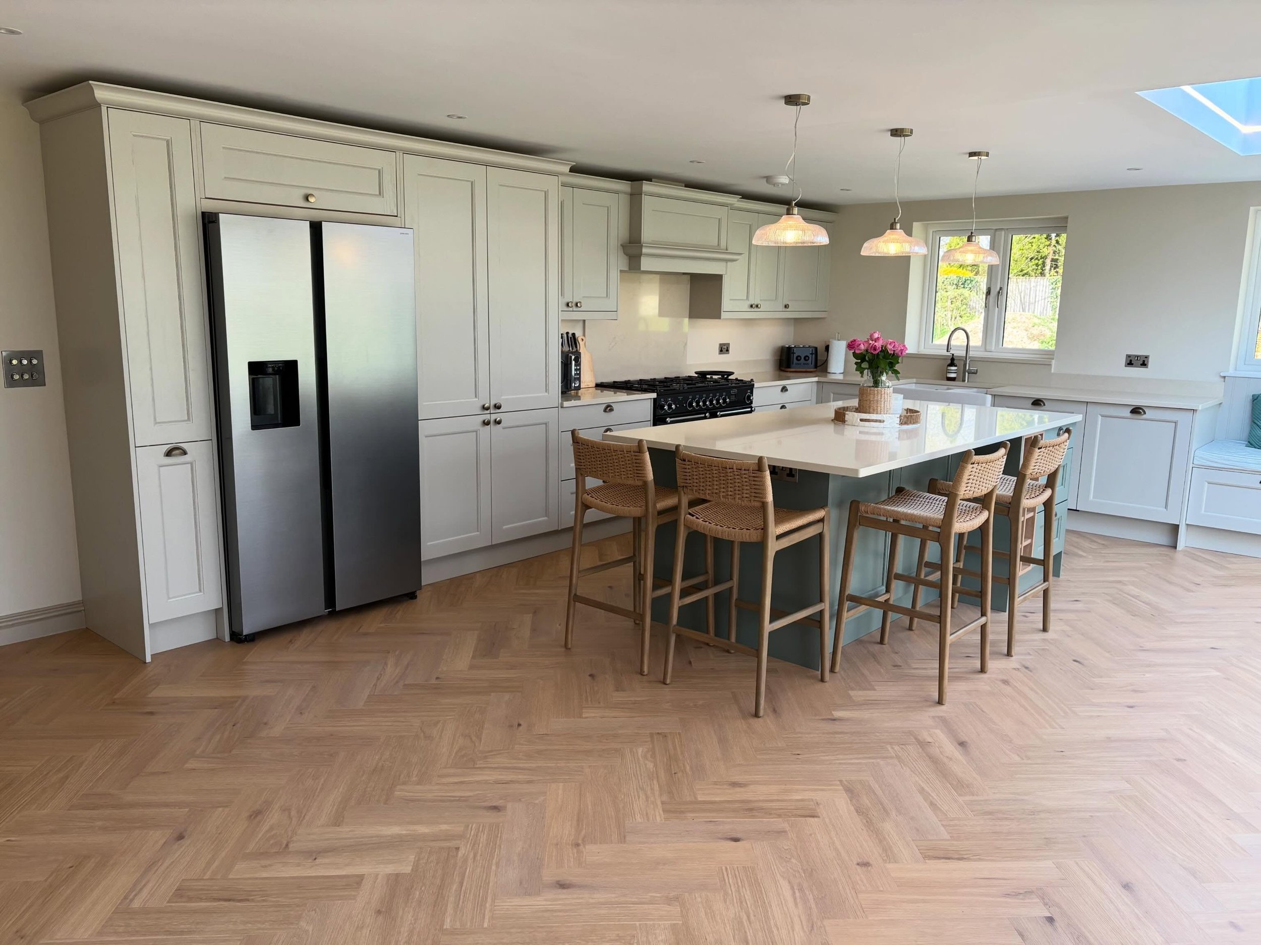 Soft sage cabinetry, a statement teal island, and that herringbone oak floor. Every detail in this Wargrave kitchen was designed to feel timeless yet completely liveable. From the integrated American fridge freezer to the range cooker and ribbed pend