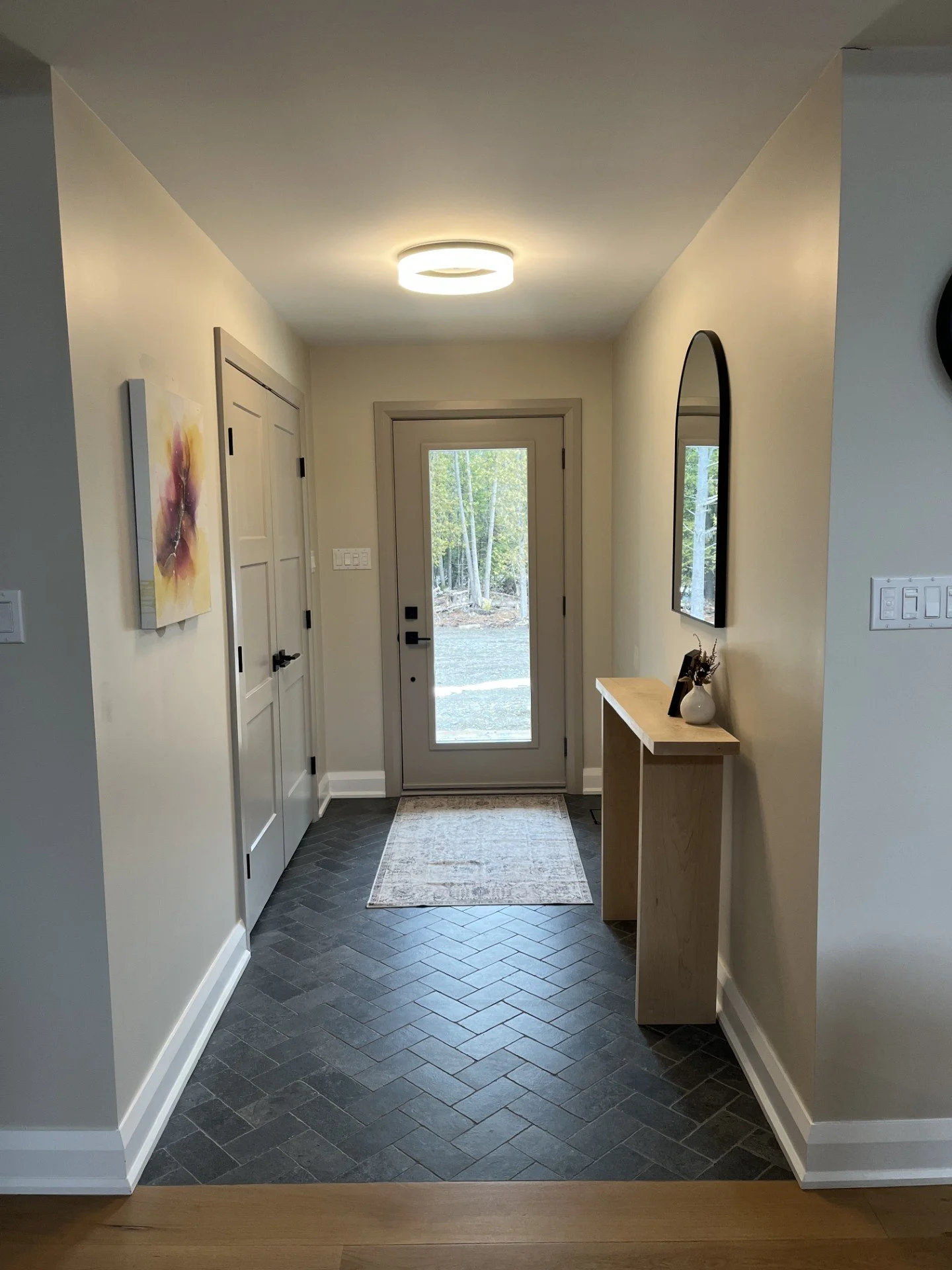 Entryway with a door, wall art, mirror, and small console table with decorations.