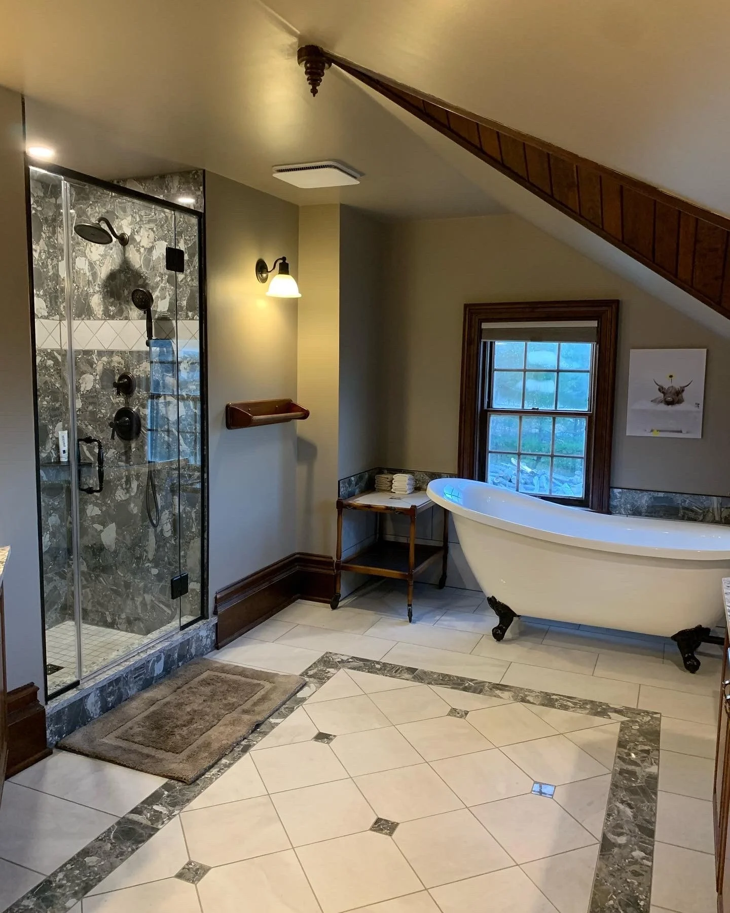 Bathroom with glass shower, clawfoot bathtub, wooden accents, a window, and decorative tile flooring.