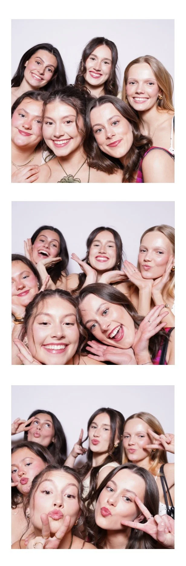 Group of six young women smiling, making funny faces, and posing for a photo booth in front of a plain white background.