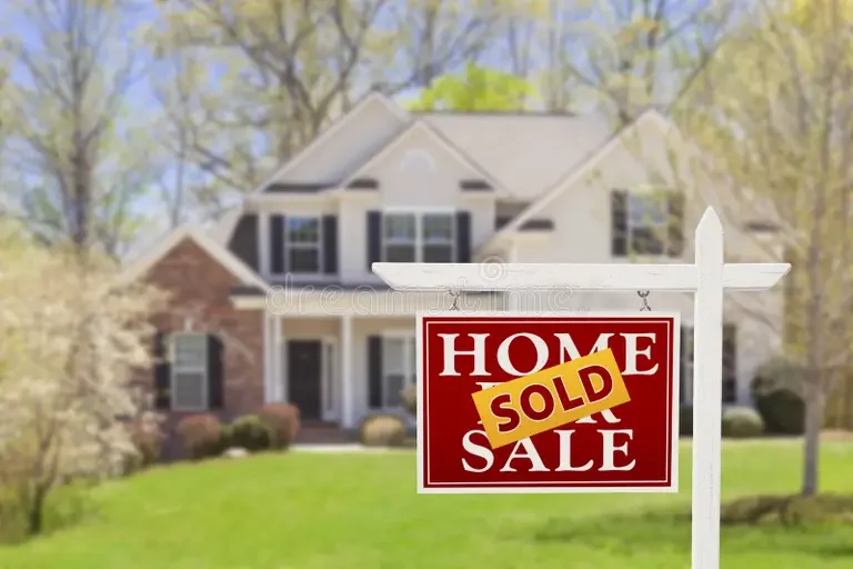 A large two-story house with a front yard and trees, with a red and white "Home Sale" sign, marked "Sold" in yellow, in the foreground.