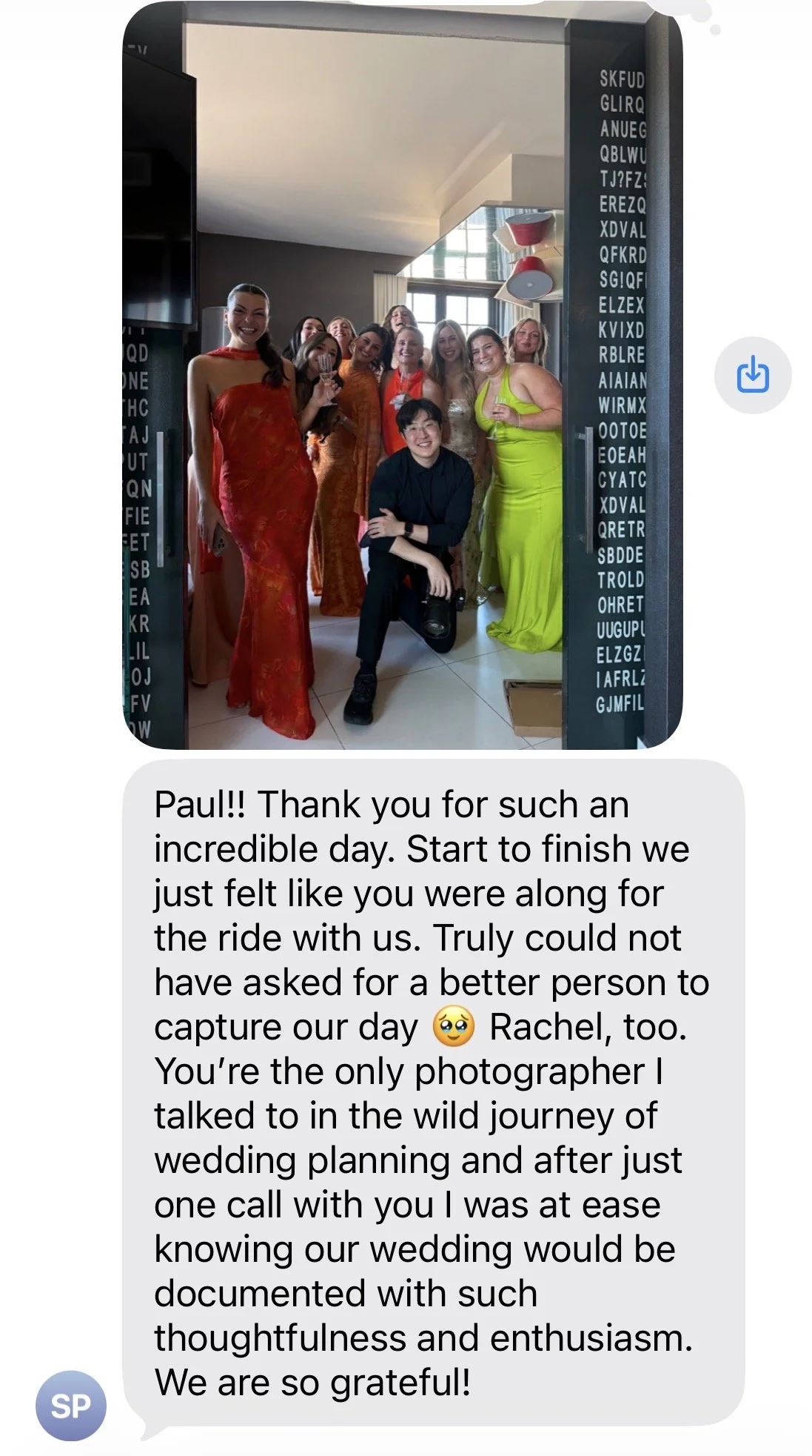 Group of women in colorful dresses smiling, taking a photo at a wedding or celebration indoors with modern decor.