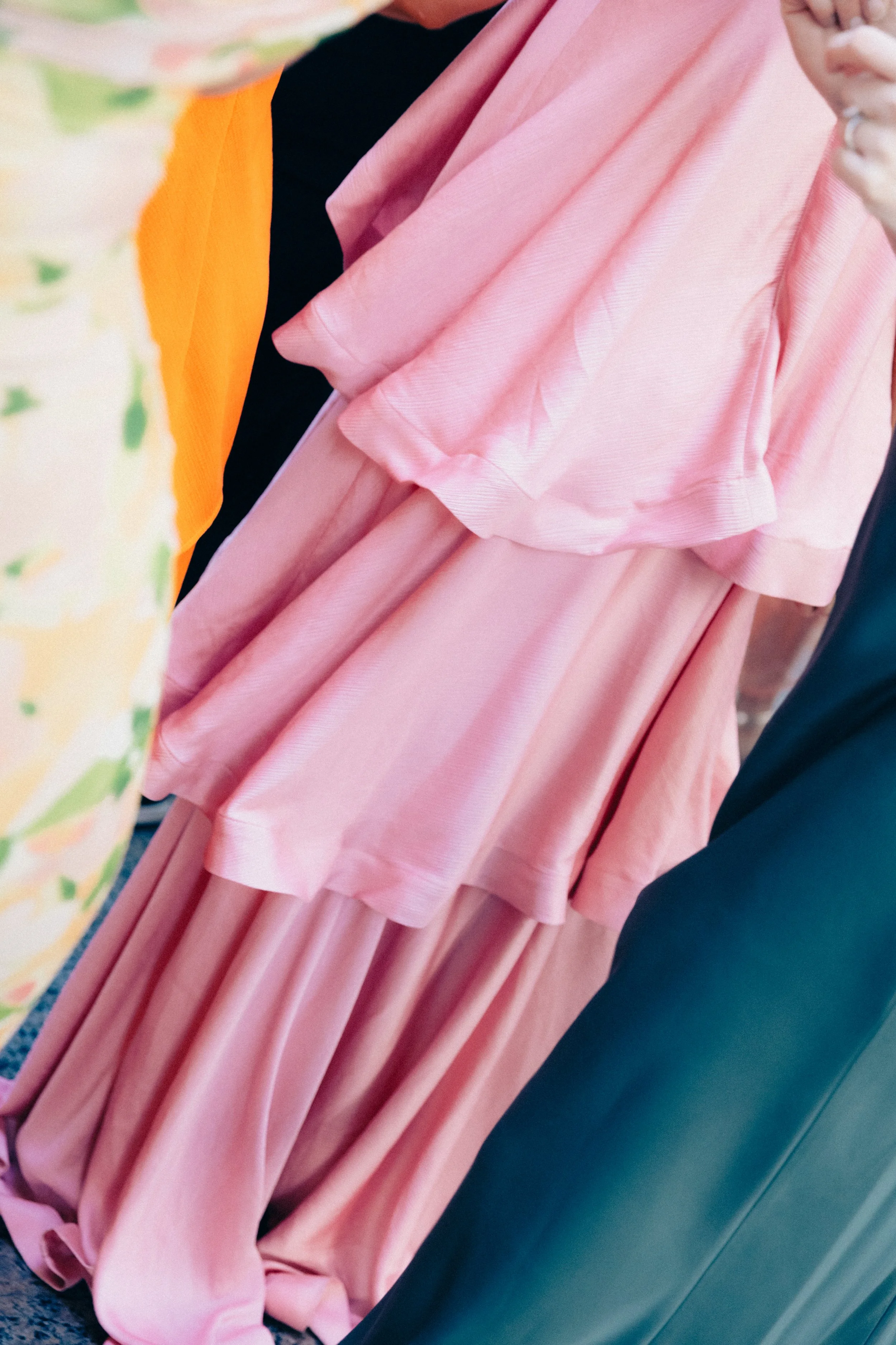 Close-up of a person wearing a pink dress sitting on a dark blue or black chair.