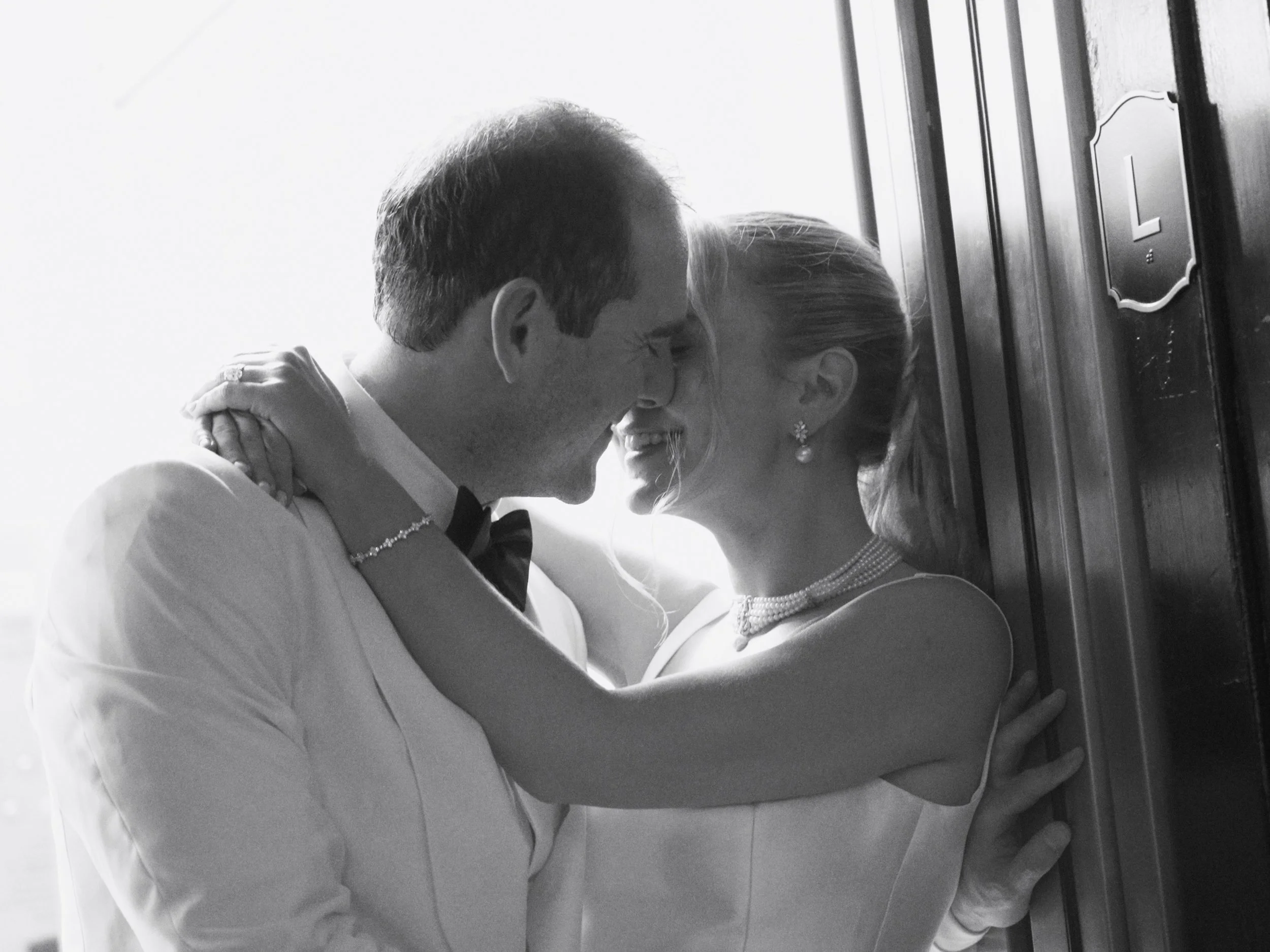 A couple in wedding attire sharing a kiss in an elevator.