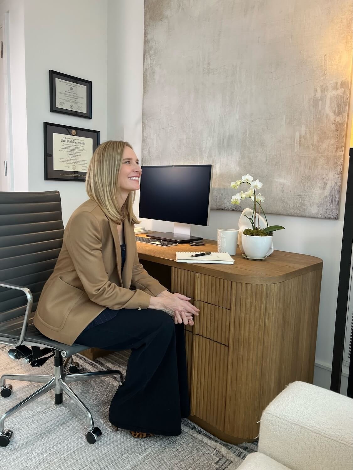 Therapist Jennifer Warpool smiling, sitting at her virtual office desk