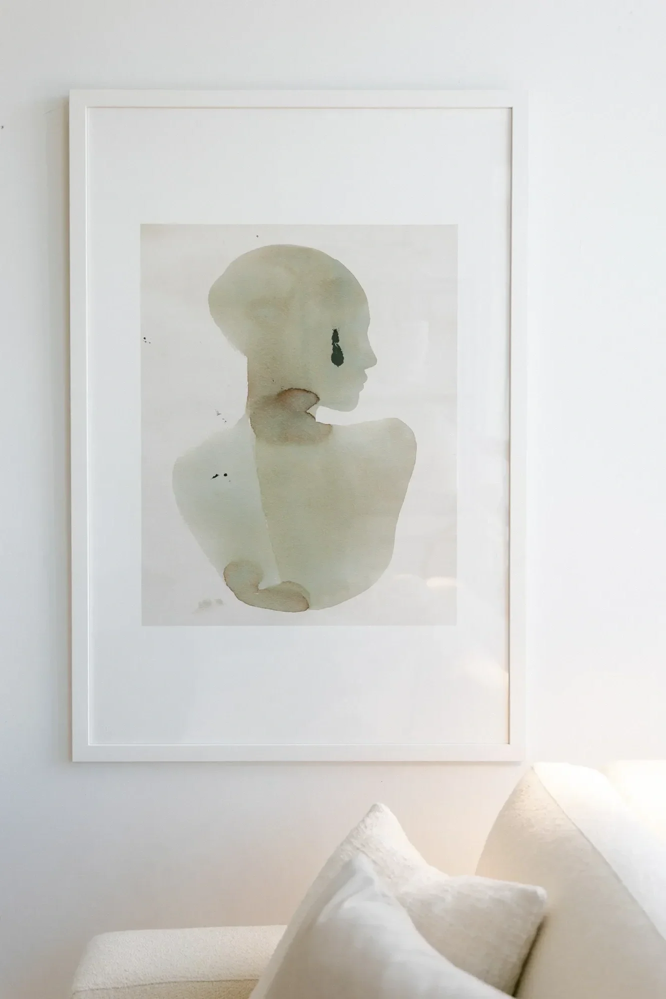 Watercolor painting of a girl hangs over a cream-colored couch