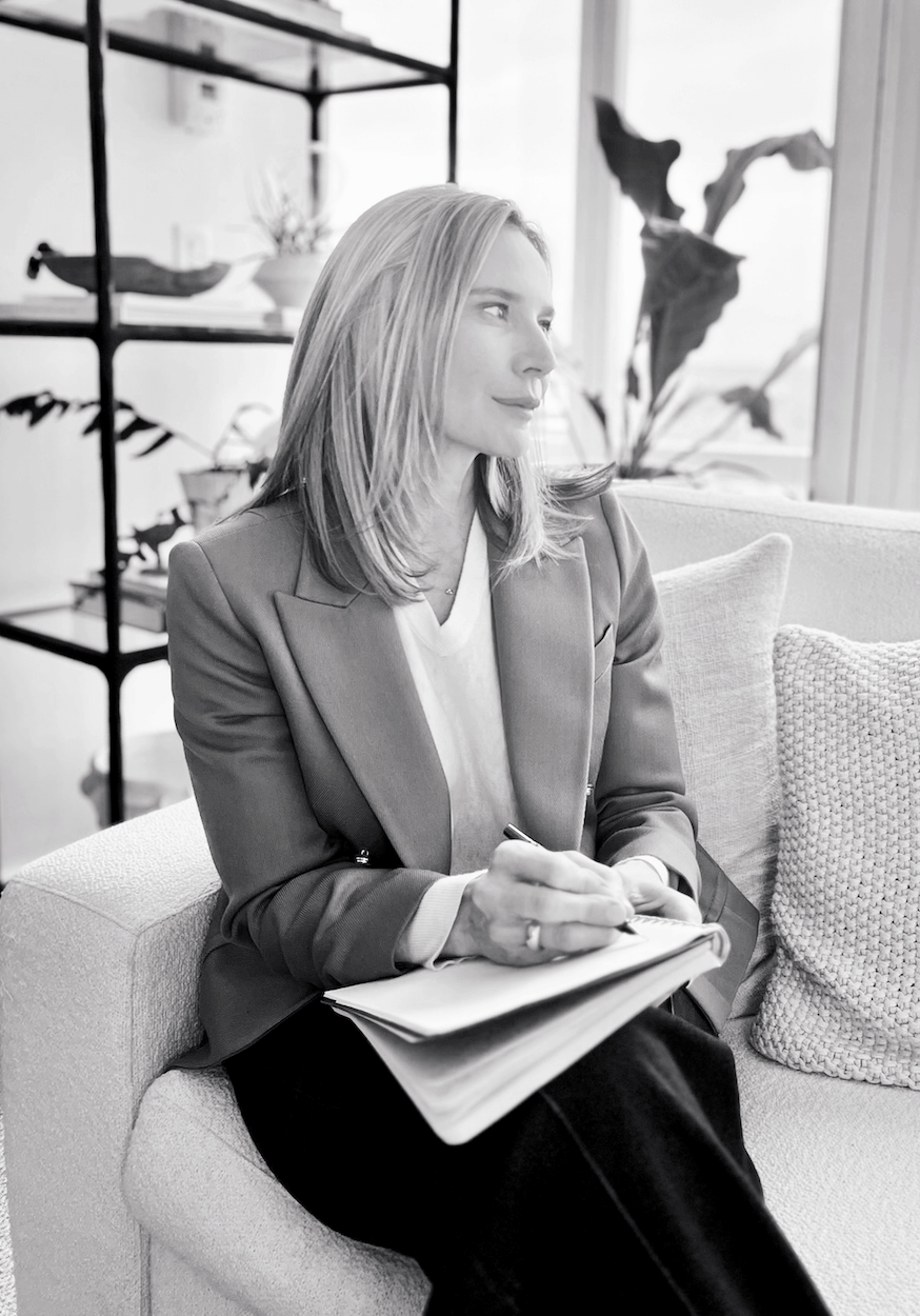 Black and white photo of eating disorder therapist Jennifer Warpool, sitting on couch with pen and journal