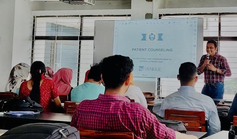 A Vennue trainer presenting at a seminar on patient counseling to an audience in a classroom or conference room with large windows.