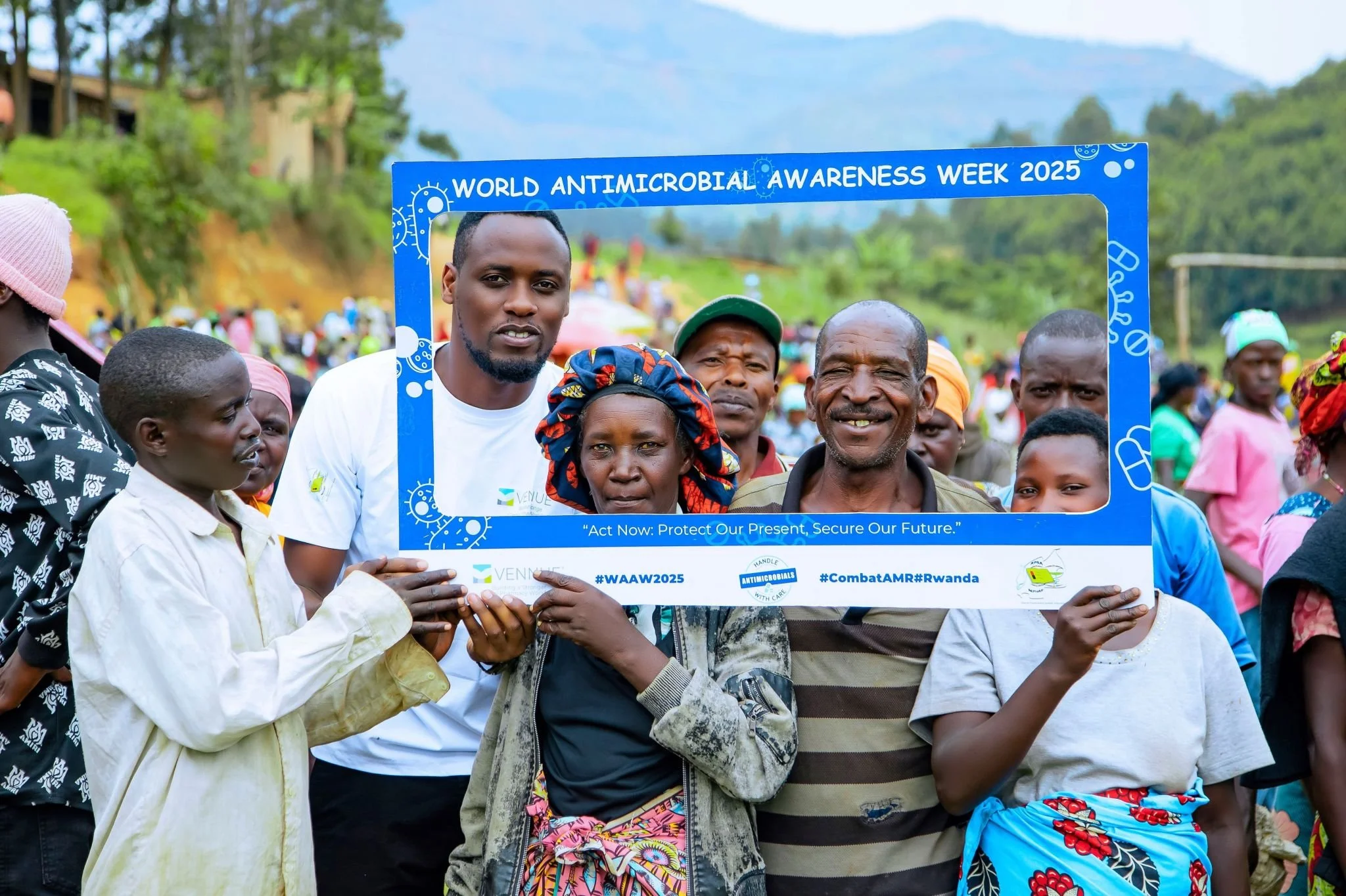 Group of people holding a blue frame that reads 'World Antimicrobial Awareness Week 2025' with the tagline 'Act Now: Protect Our Present, Secure Our Future,' at an outdoor event in Rwanda.