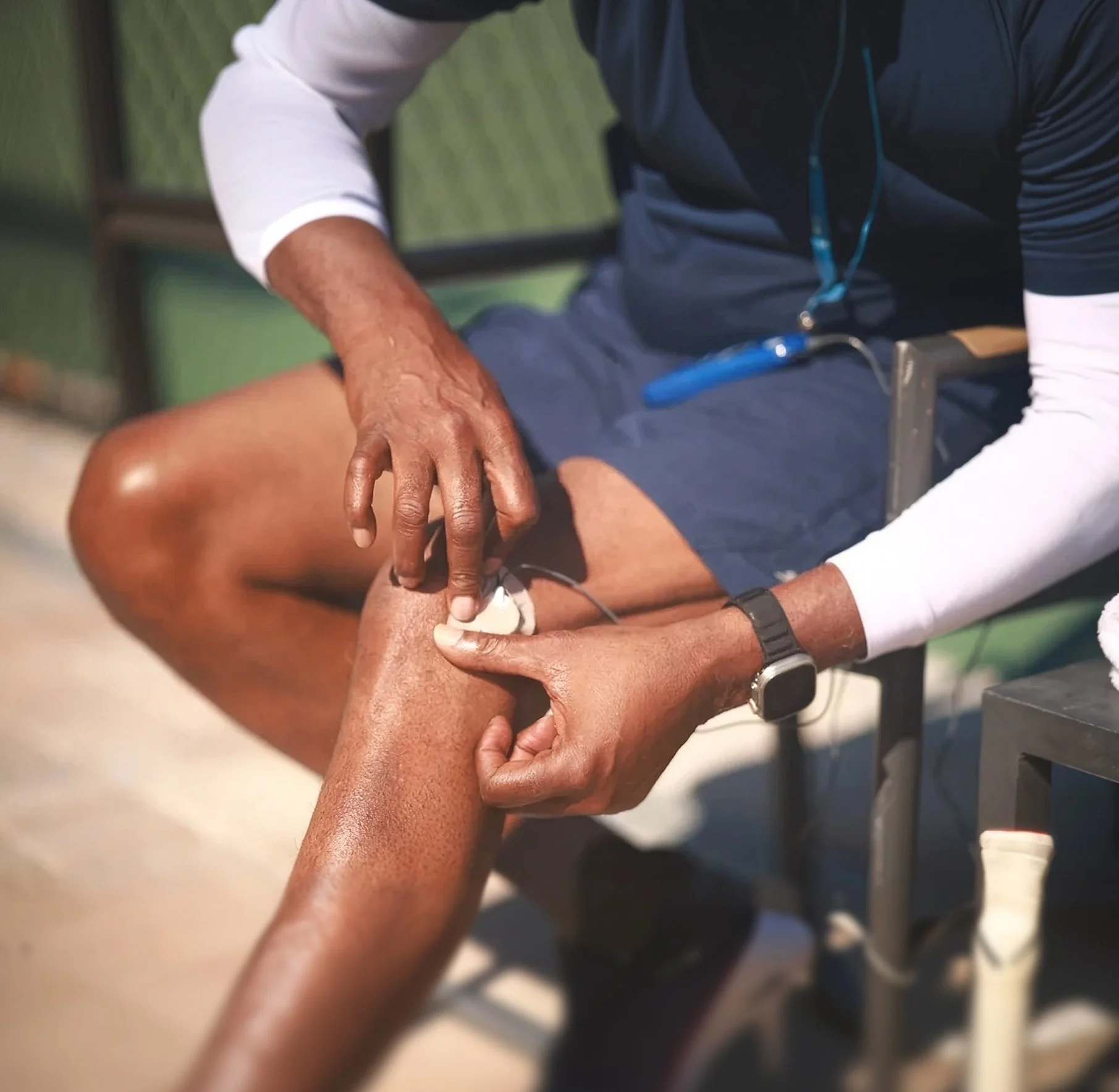 A healthcare professional performing a medical procedure on a patient's leg in a clinical setting.