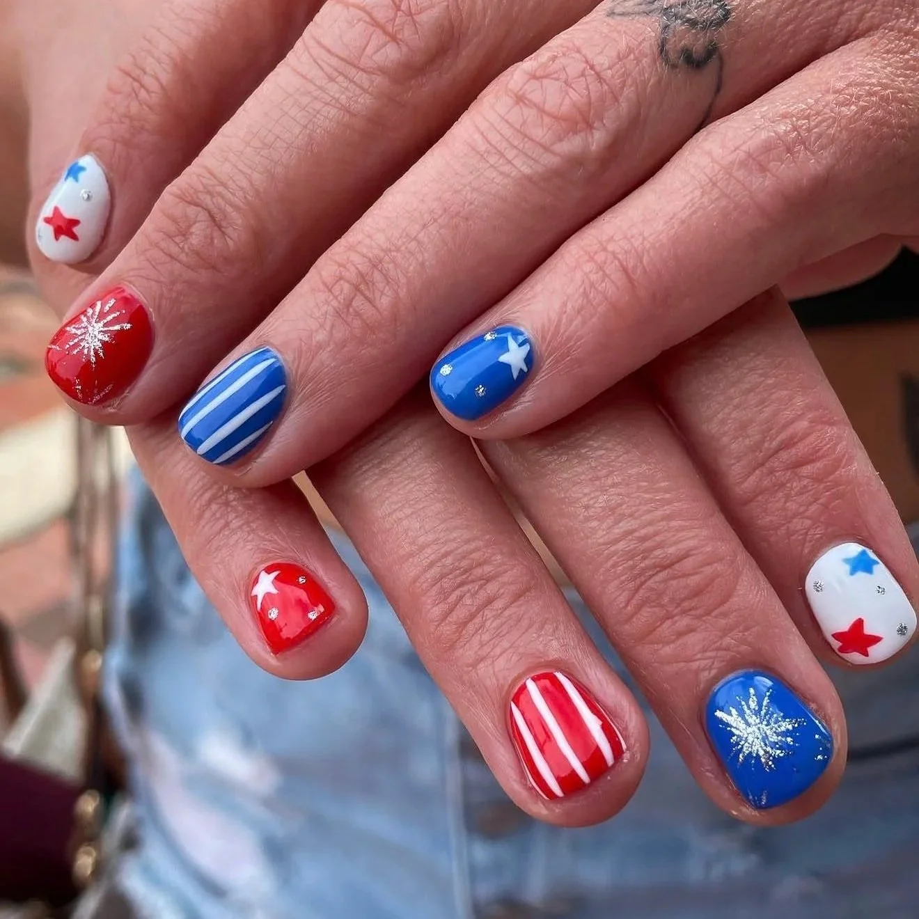 Nail art with red, white, and blue colors, featuring stars, snowflakes, stripes, and snowflake patterns, reflecting a patriotic or festive by Salon 230 Daytona Beach