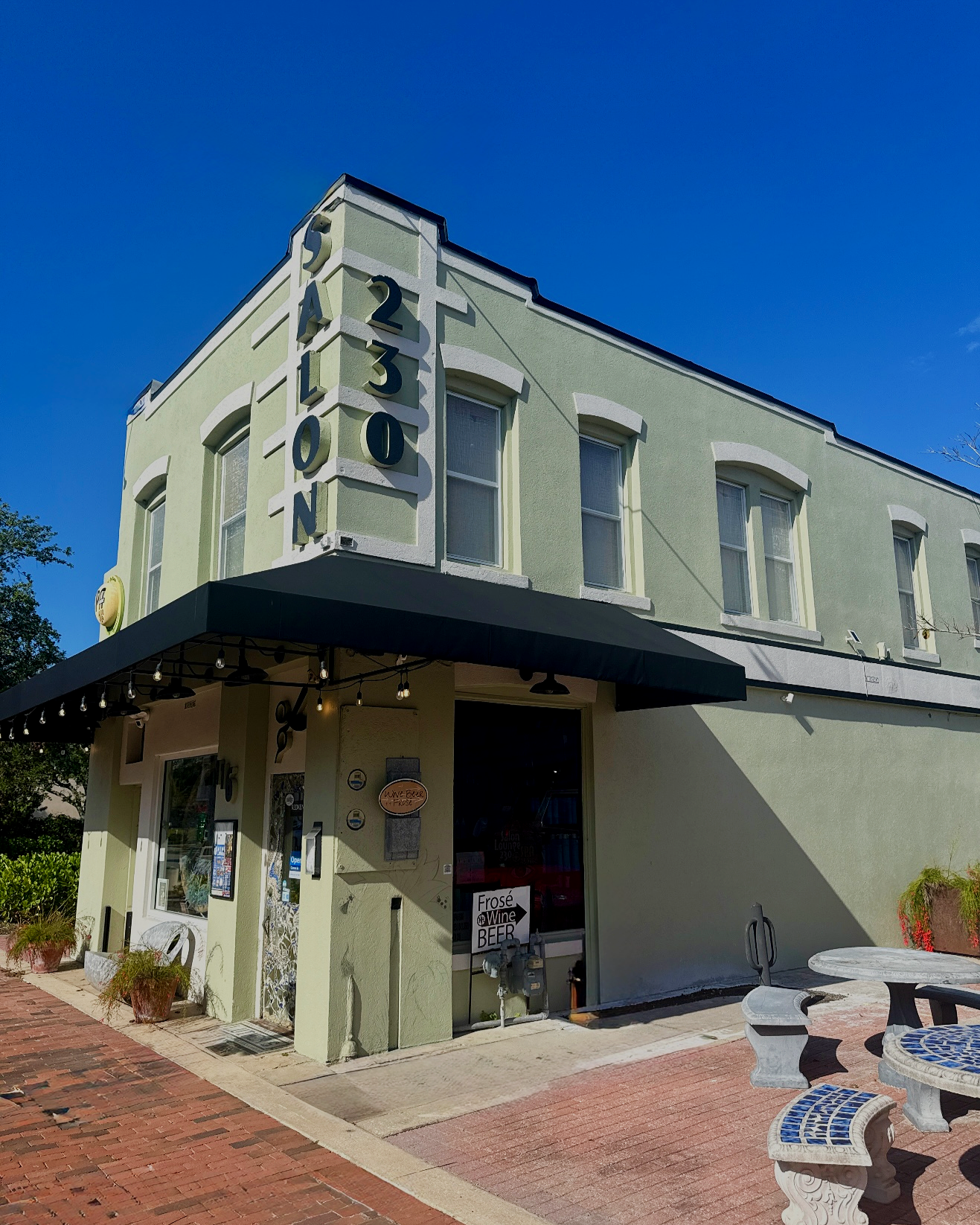 Exterior of Salon 230 Spa above a full service salon and spa in Downtown Daytona Beach selling wine, beer, and frose, with outdoor seating and string lights.