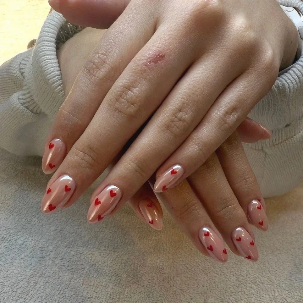 Pink nail polish decorated with small red hearts and chrome nails by Salon 230 Daytona Beach