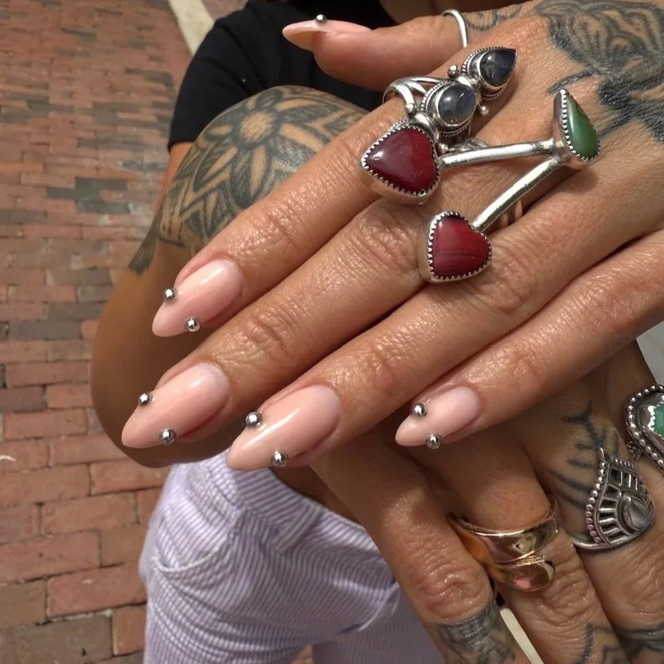 Well-manicured set of builder gel nail extensions with silver ball piercing accents by Salon 230 Daytona Beach