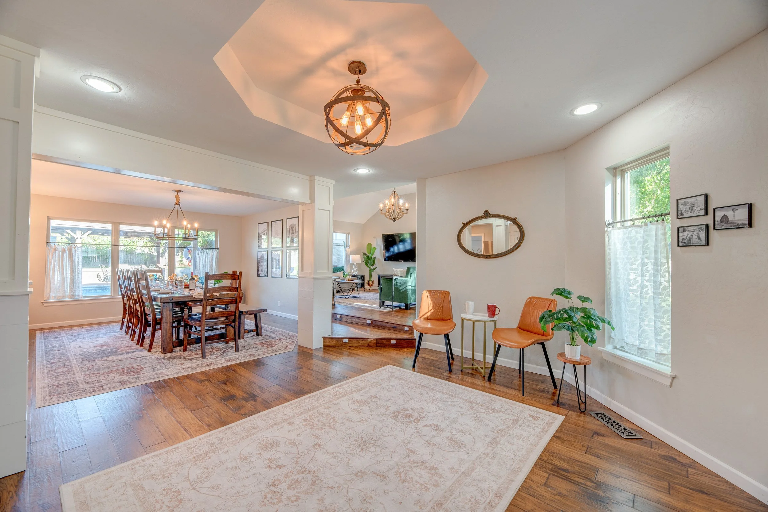 Open-concept living and dining area with natural light, hardwood floors, modern light fixtures, and minimal decor.