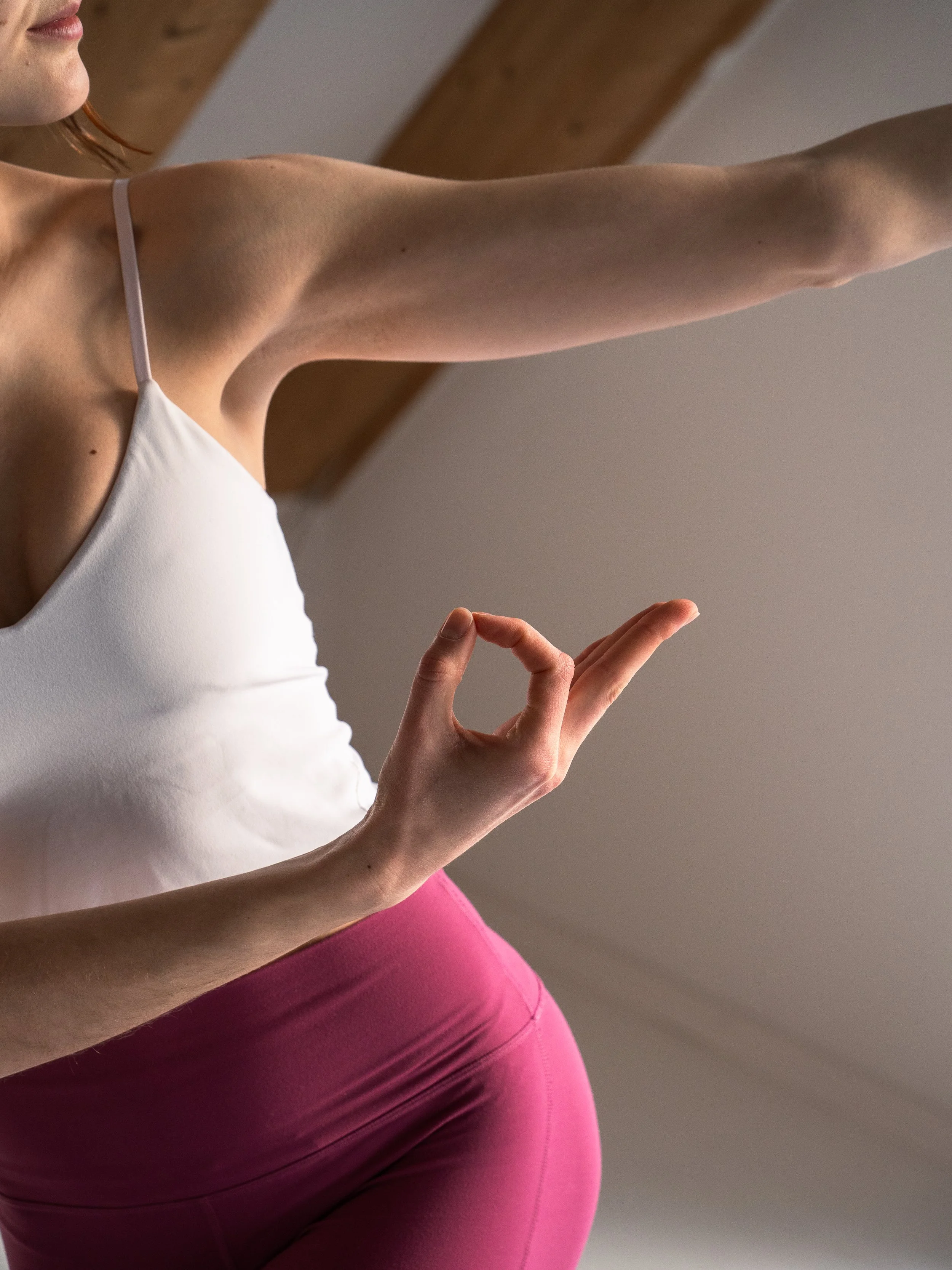 Eine junge Frau macht Yoga im Raum, die Hand bildet einen Kreis in der Meditation