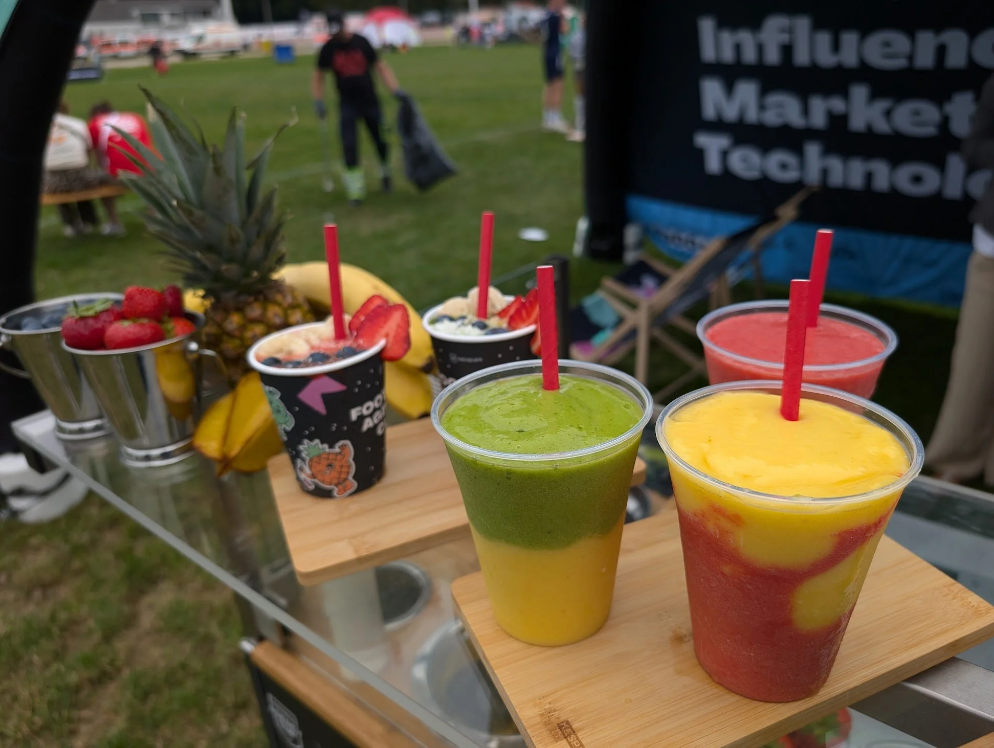 Bunte Fruchtsäfte und frische Früchte auf einem Marktstand im Freien.