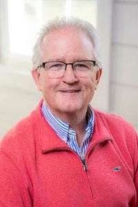 Professional corporate headshot of board member smiling in a bright modern office.