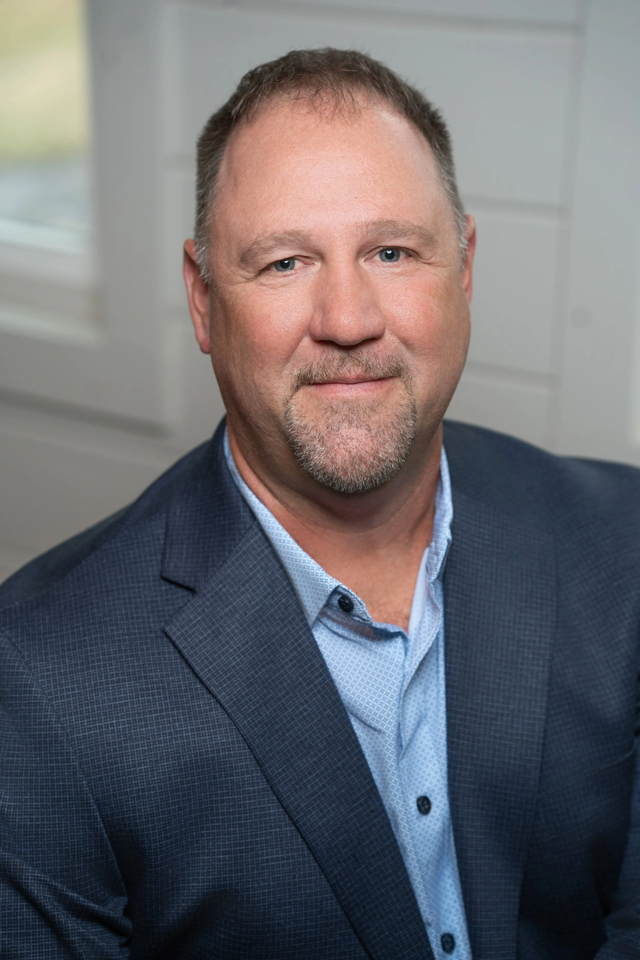 Professional corporate headshot of board member smiling in a bright modern office.