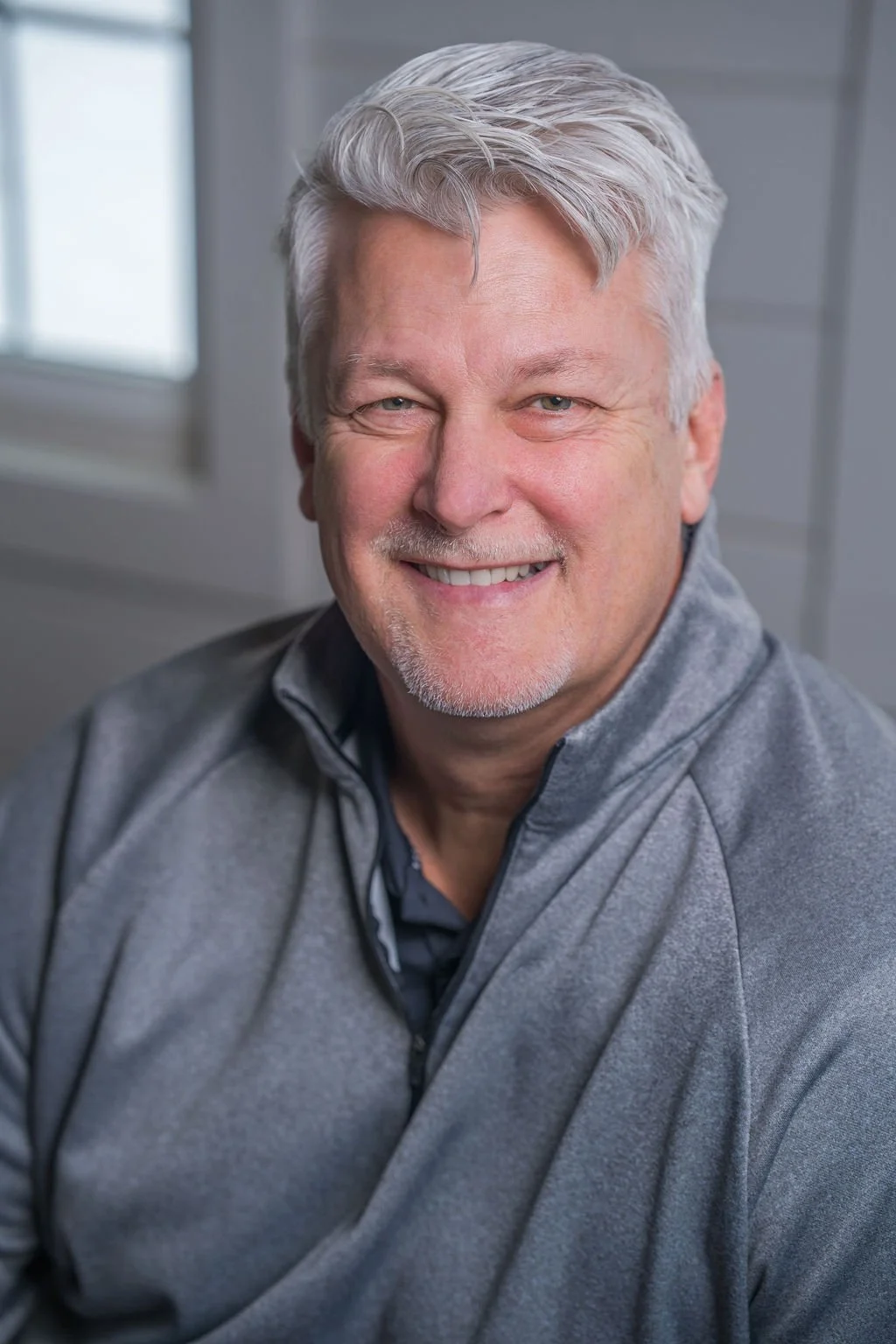 Professional corporate headshot of board member smiling in a bright modern office.