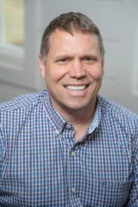 Professional corporate headshot of board member smiling in a bright modern office.