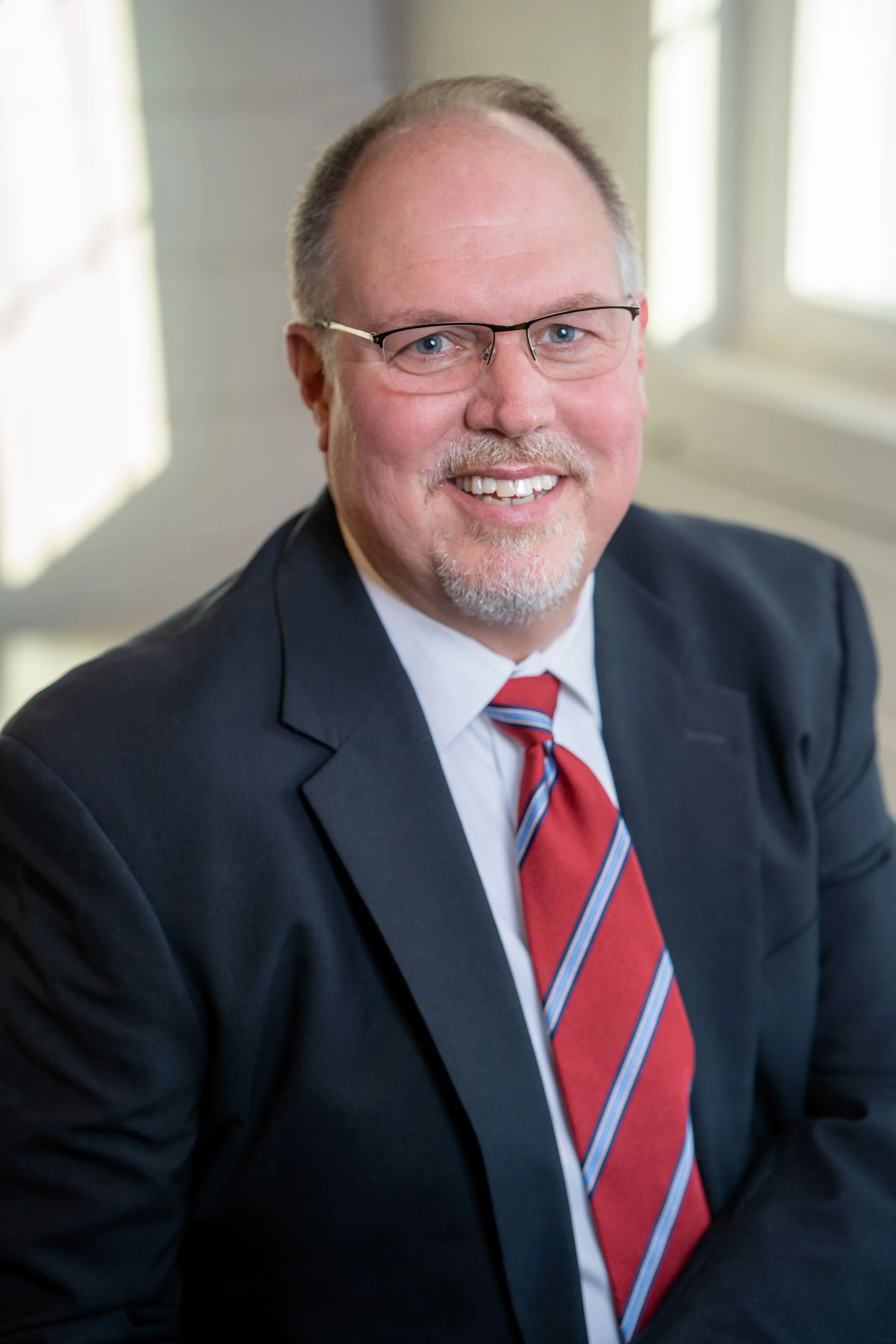 Professional corporate headshot of board member smiling in a bright modern office.