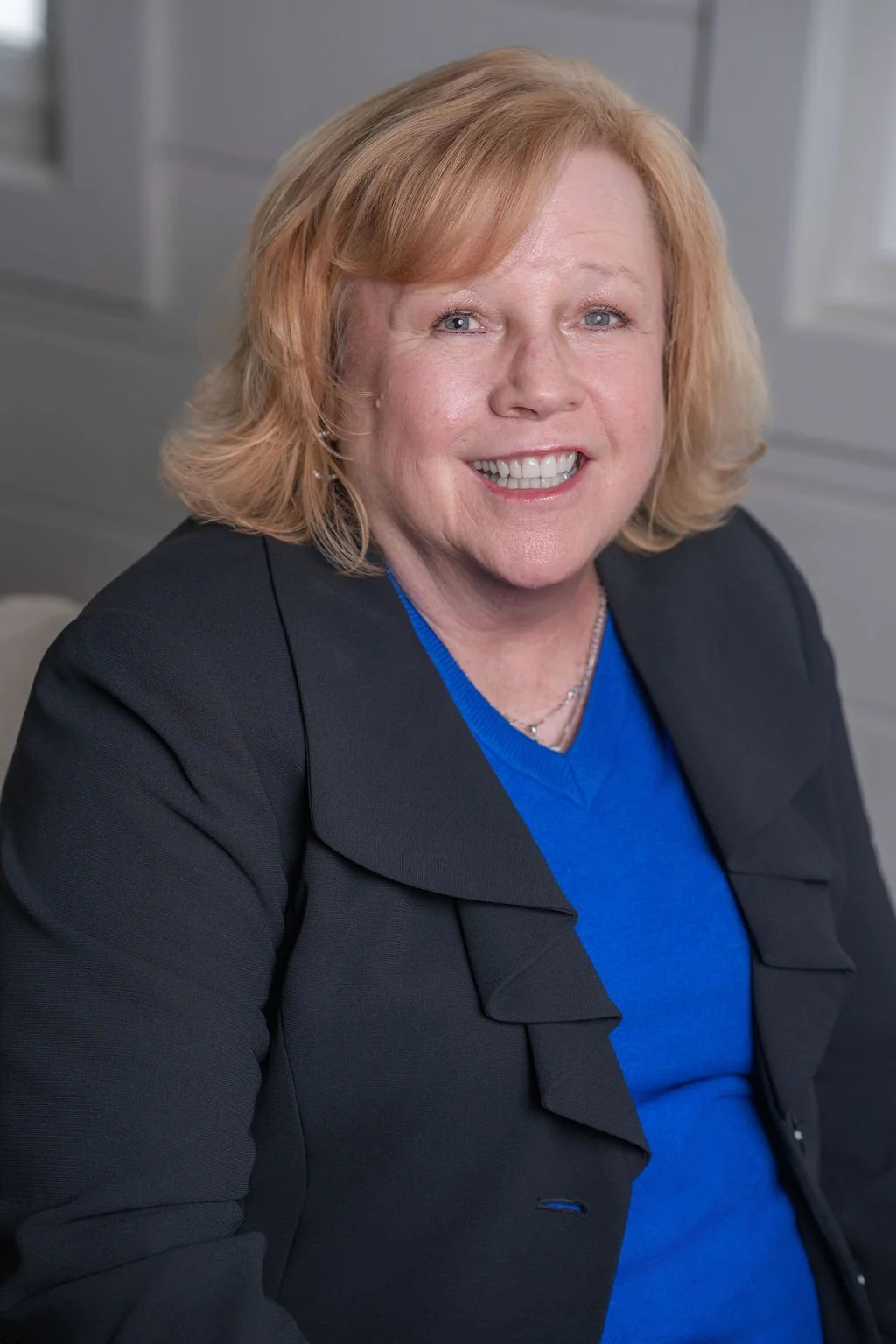 Professional corporate headshot of board member smiling in a bright modern office.