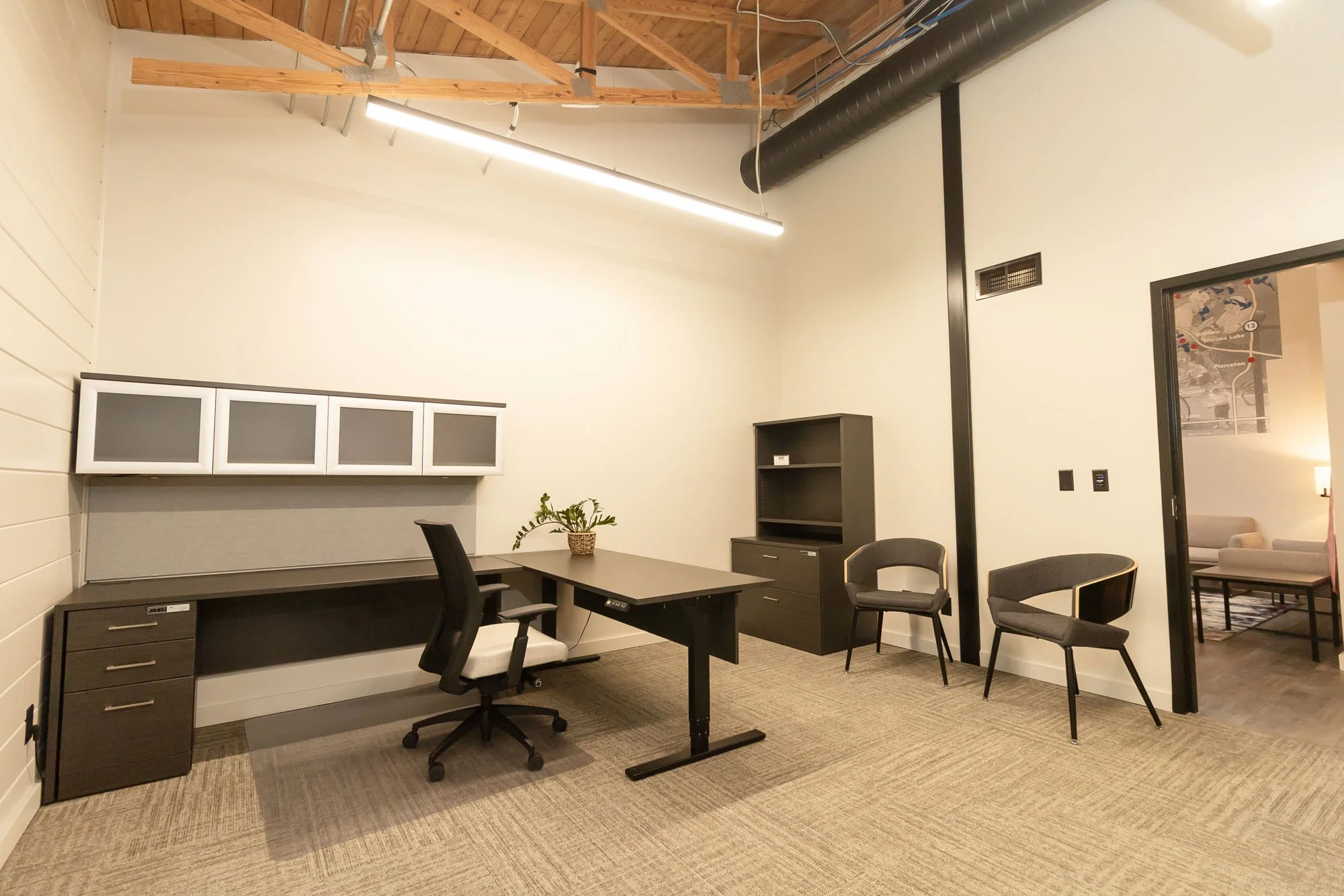 Warm large office space with "L" shape desk and three chairs