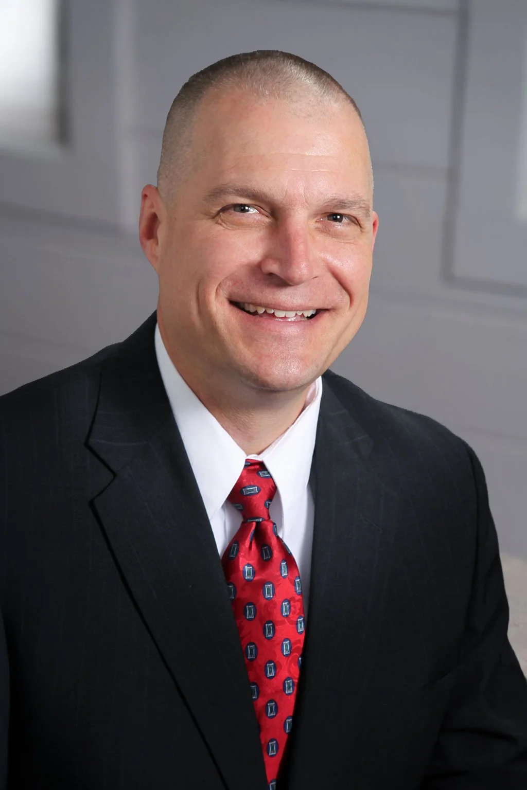 Professional corporate headshot of board member smiling in a bright modern office.