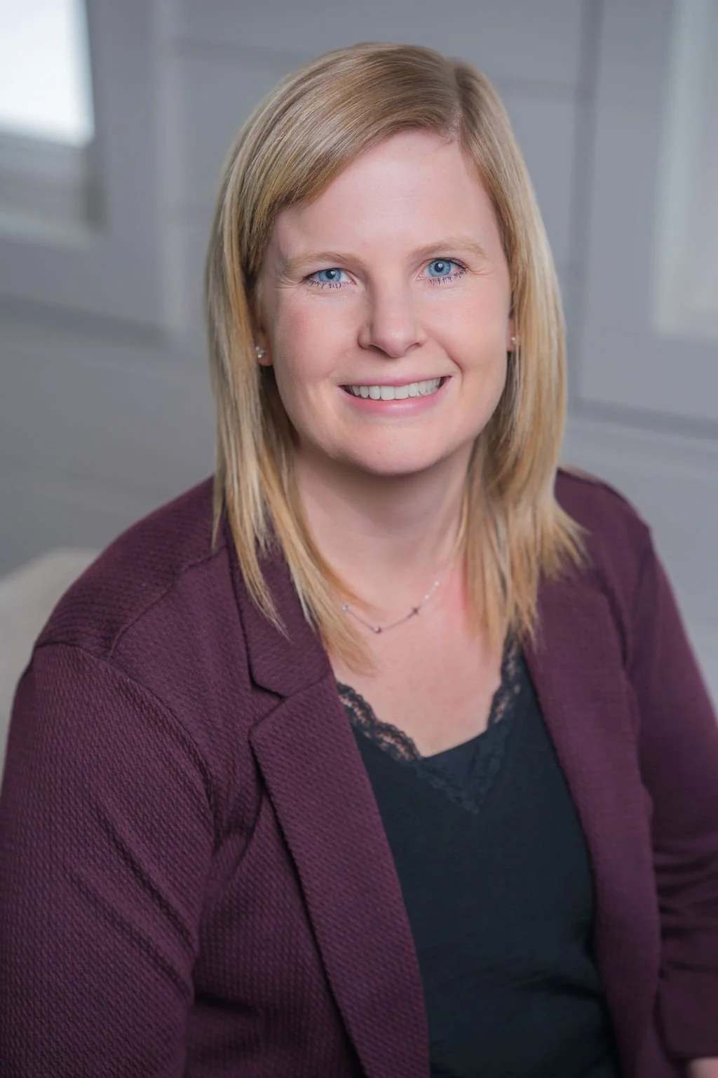 Professional corporate headshot of board member smiling in a bright modern office.