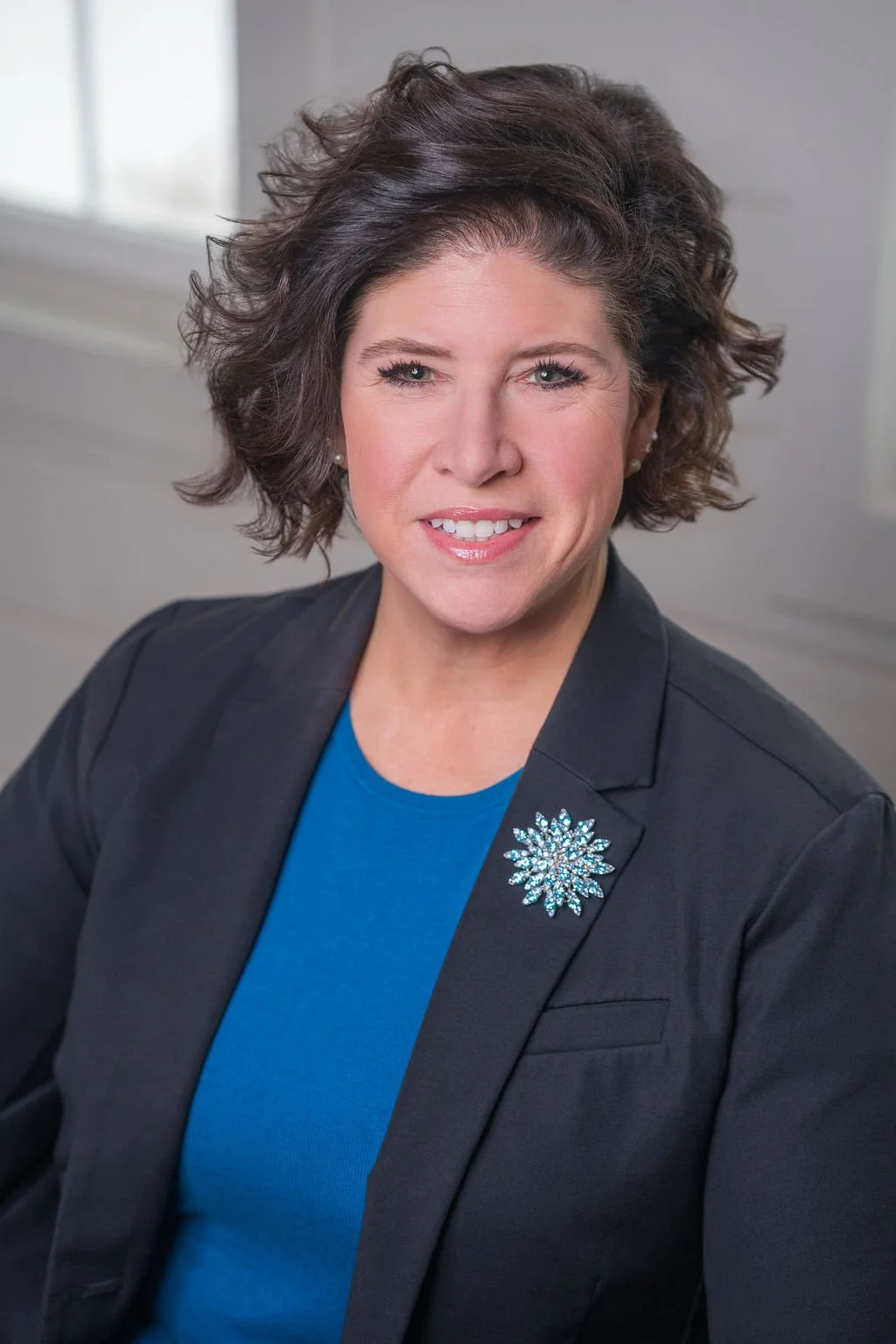 Professional corporate headshot of board member smiling in a bright modern office.