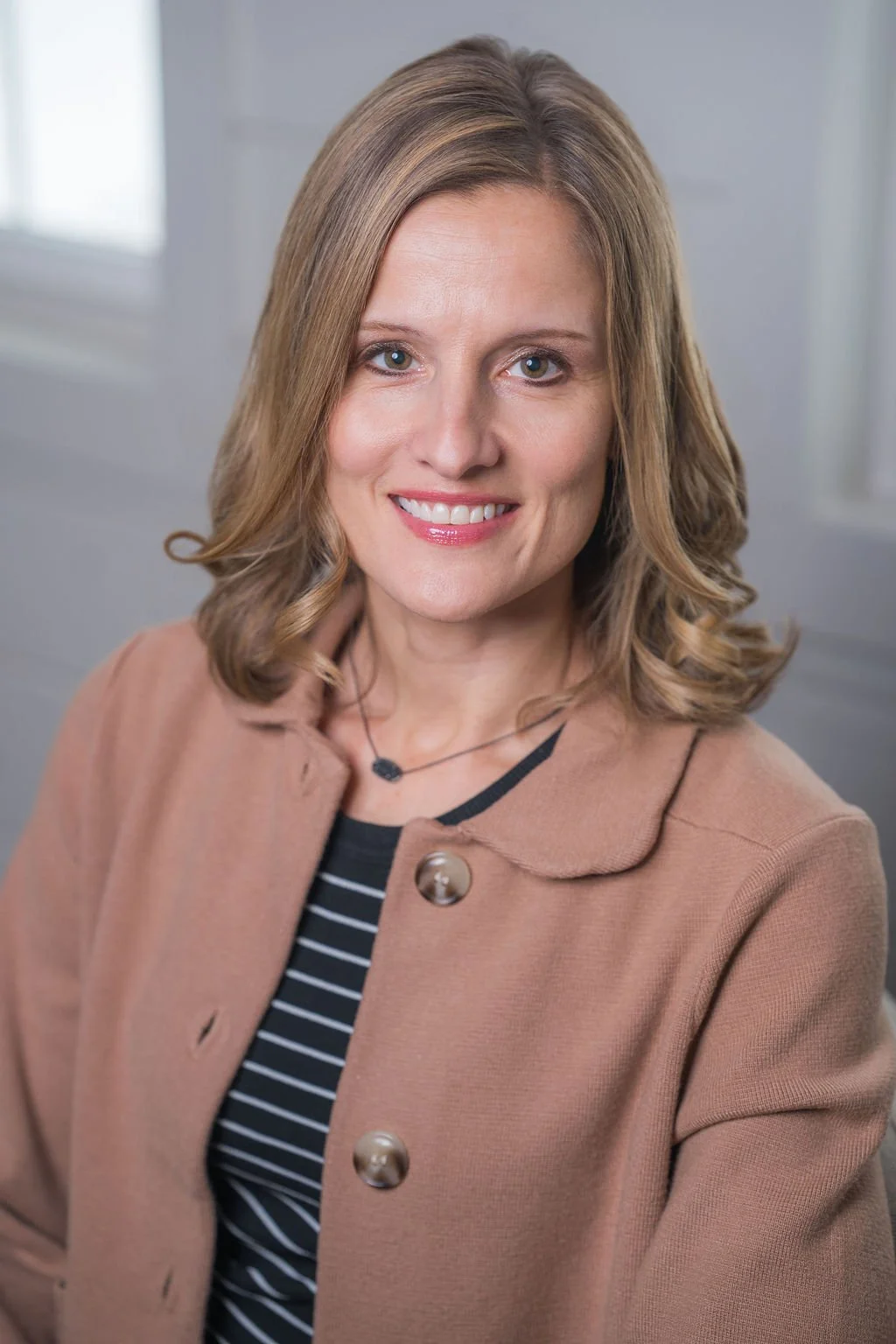 Professional corporate headshot of board member smiling in a bright modern office.