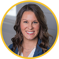 Professional corporate headshot of Angie smiling in a bright modern office.