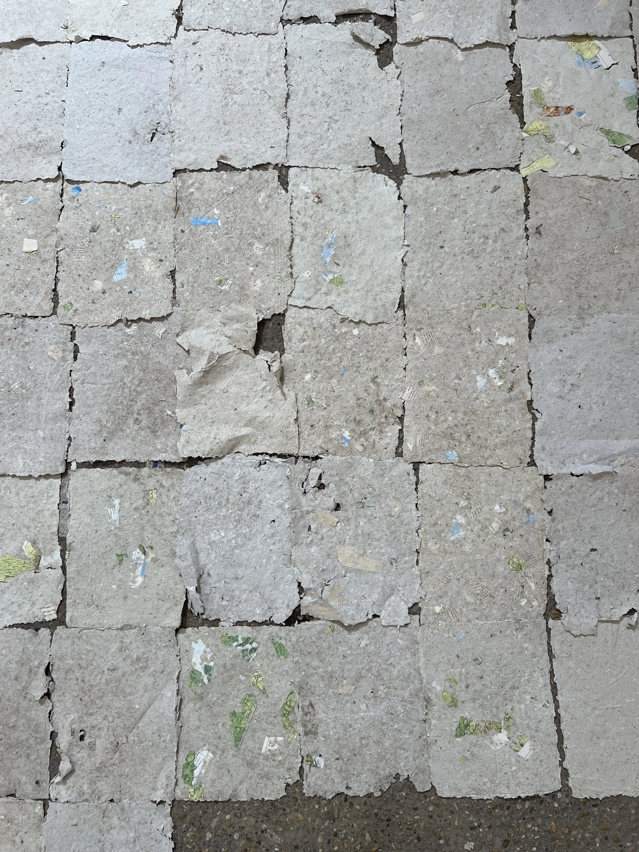 Cracked concrete pavement with scattered pieces of torn paper and debris.