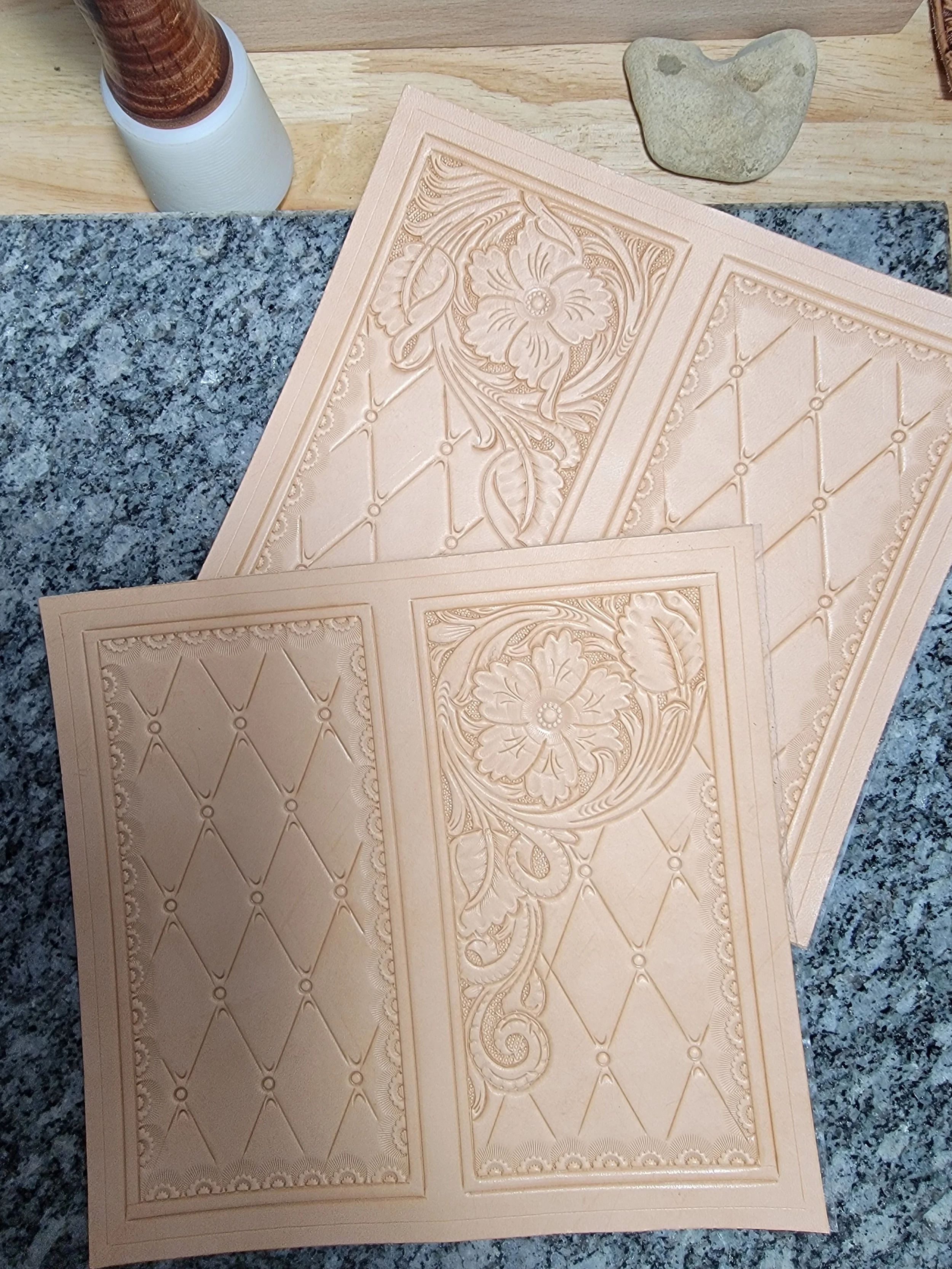Three embossed beige tiles with floral and geometric patterns on a kitchen countertop.