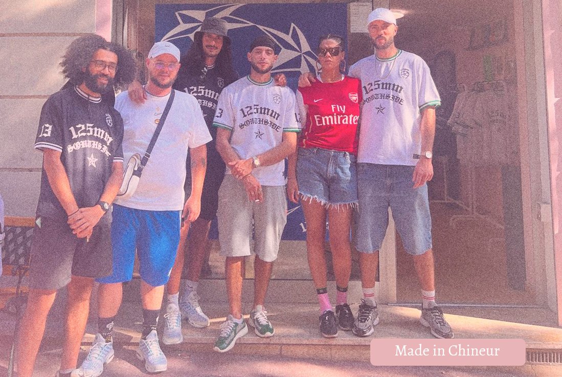Group of six people standing in front of a wall with a star logo, dressed in casual and sportswear, with a sign reading "Made in Chineur" at the bottom.