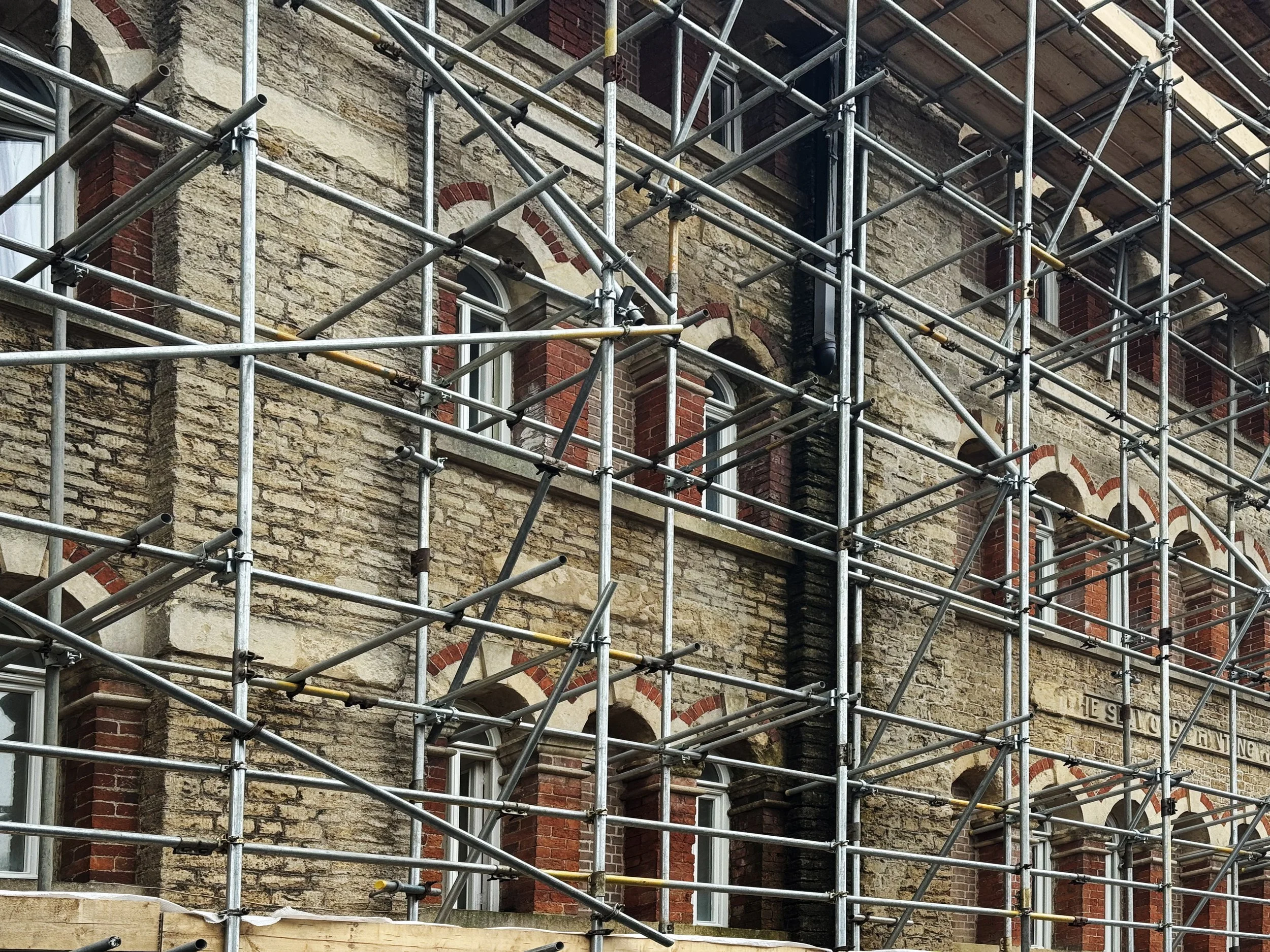 Exterior of a historic brick building under renovation, surrounded by scaffolding.