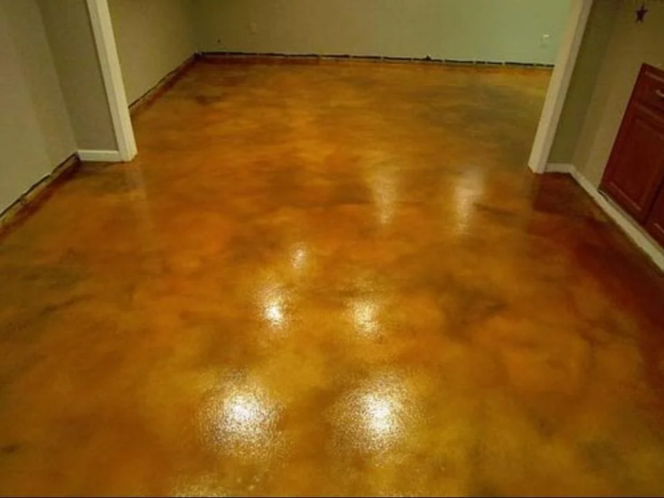 Shiny polished hardwood floor in a room with beige walls and white baseboards.