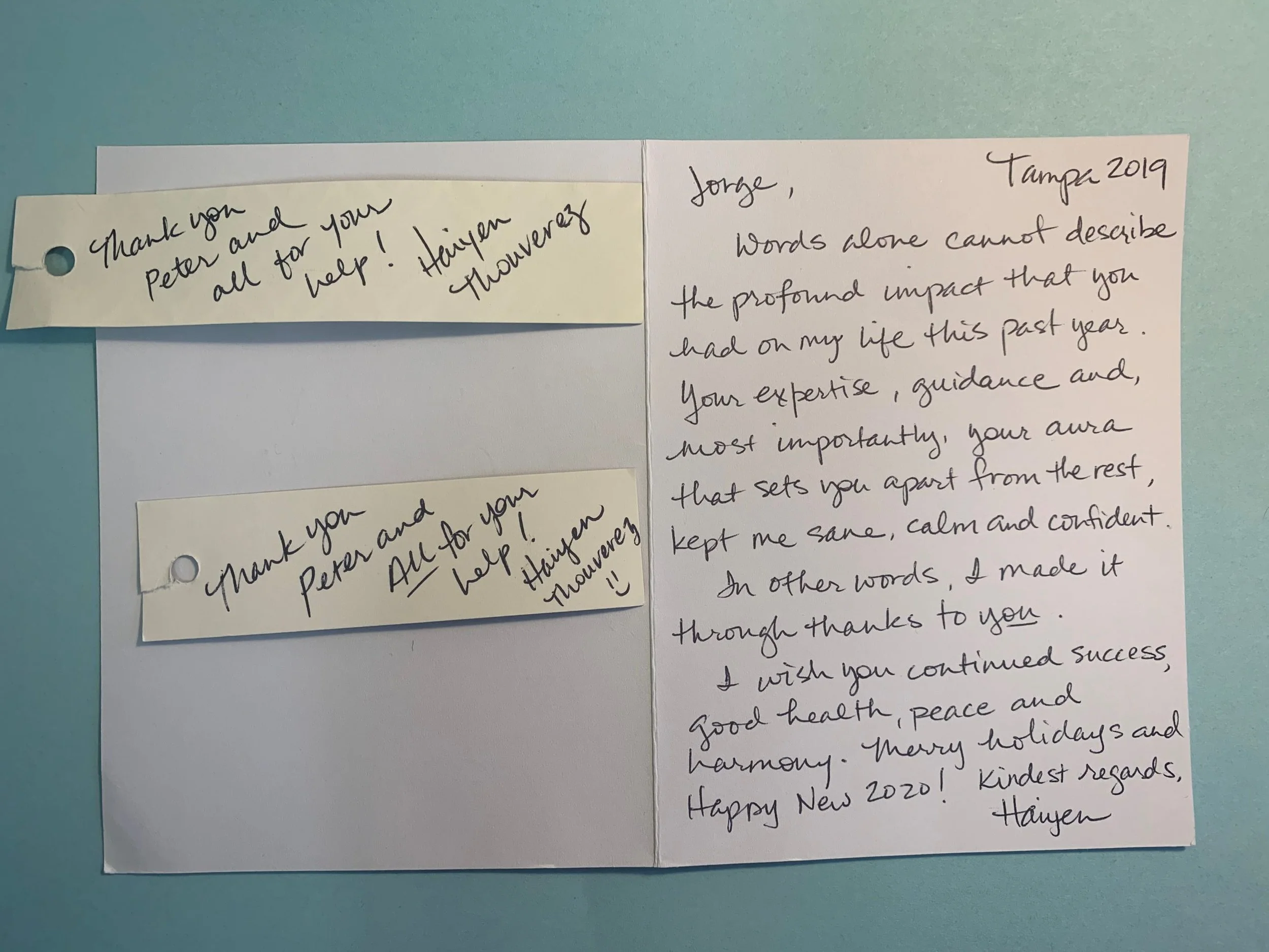 Close-up of handwritten thank you notes on paper, with motivational message and holiday wishes.