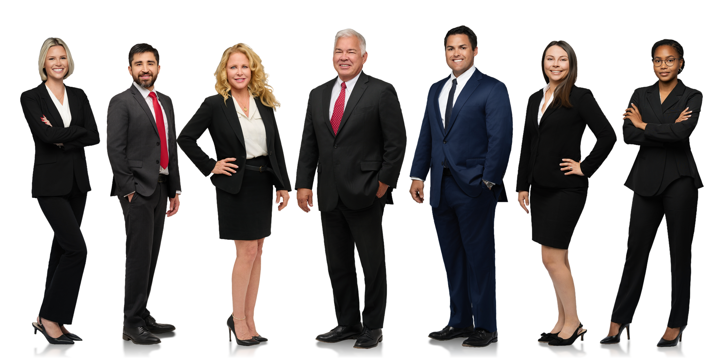 Group of seven professionally dressed individuals standing in a row against a black background, smiling and looking at the camera.