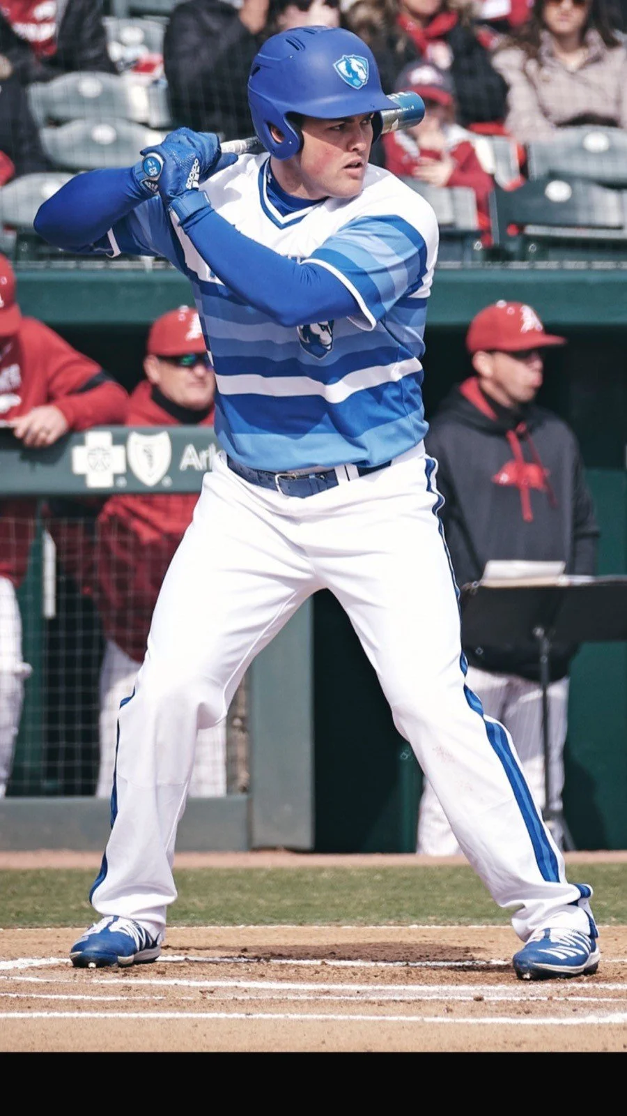 A baseball player in a blue and white uniform prepares to bat during a game.