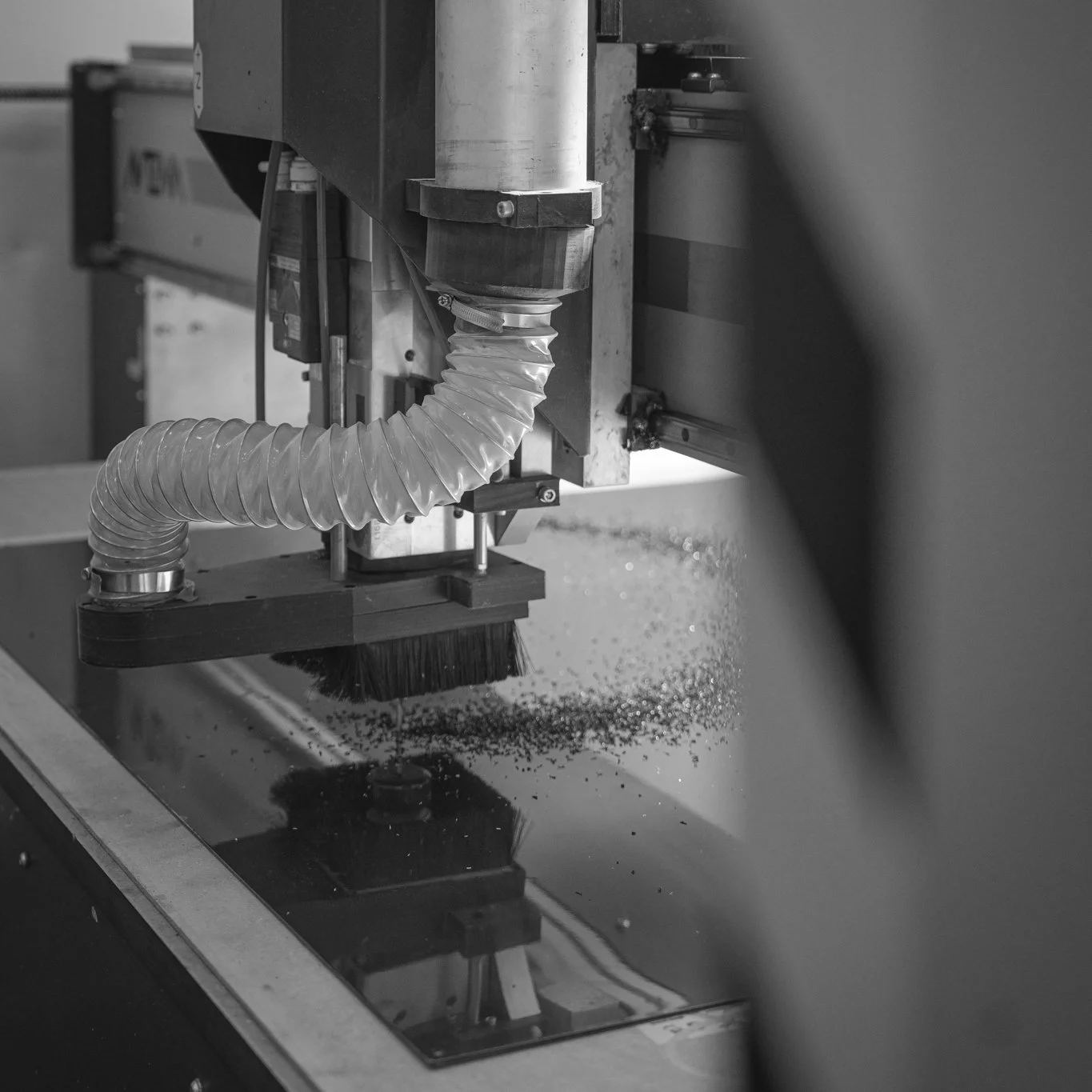 Close-up of a CNC machine tool cutting into a material, with metal shavings on the work surface.