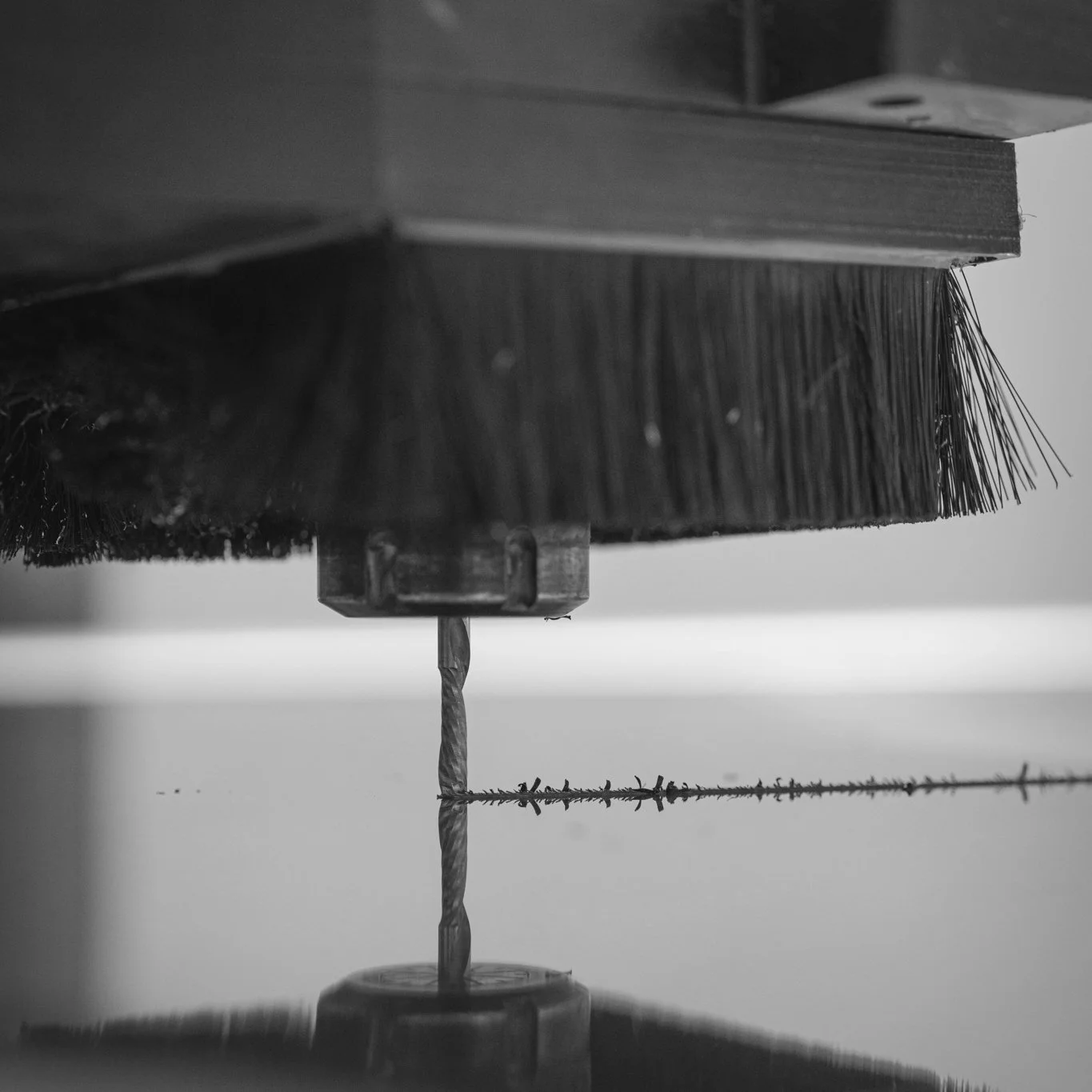 Close-up of a broom with a wooden handle, mounted upside down with the bristles facing downward, against a plain background.