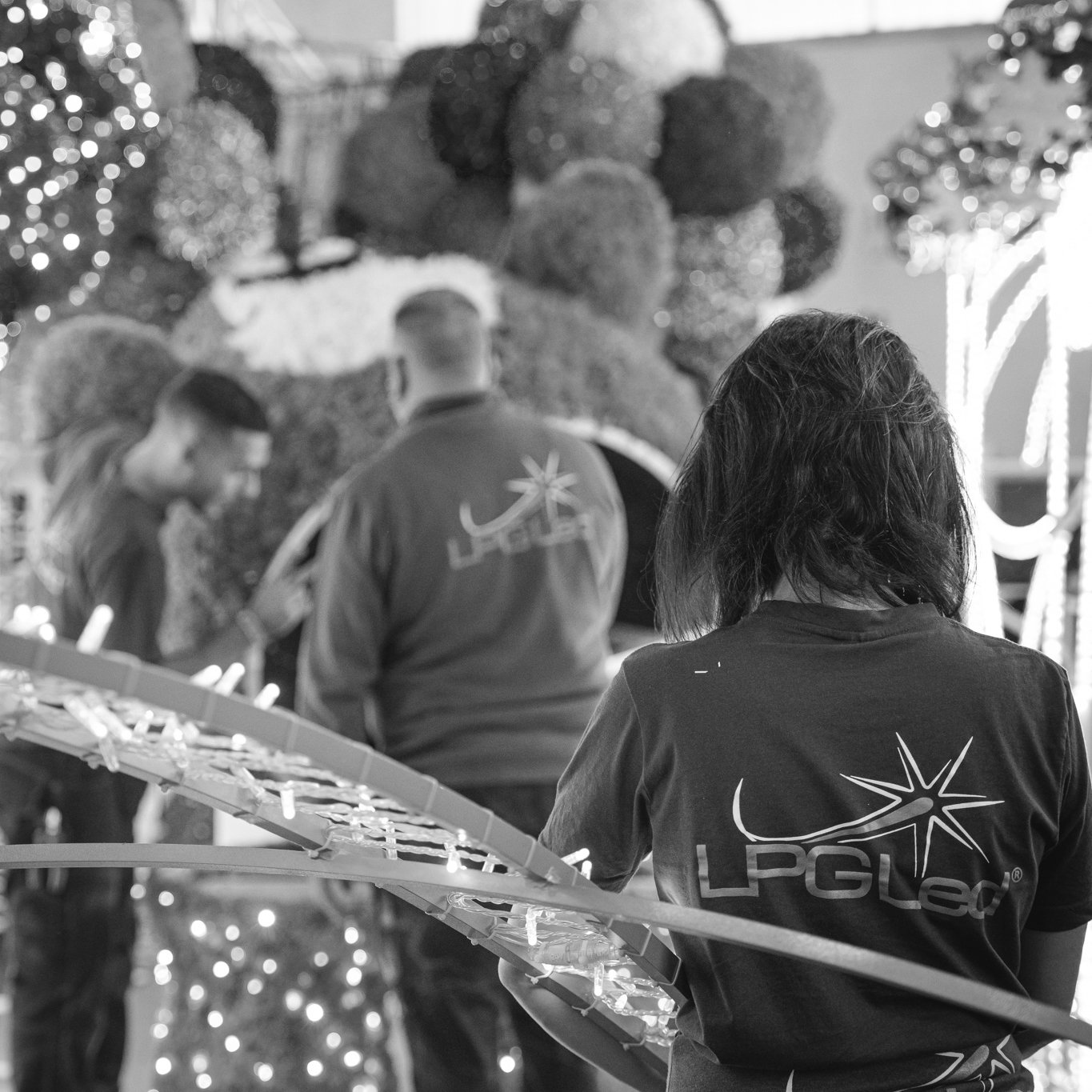 People riding a carnival Ferris wheel at night, with festive lights and holiday decorations in the background.