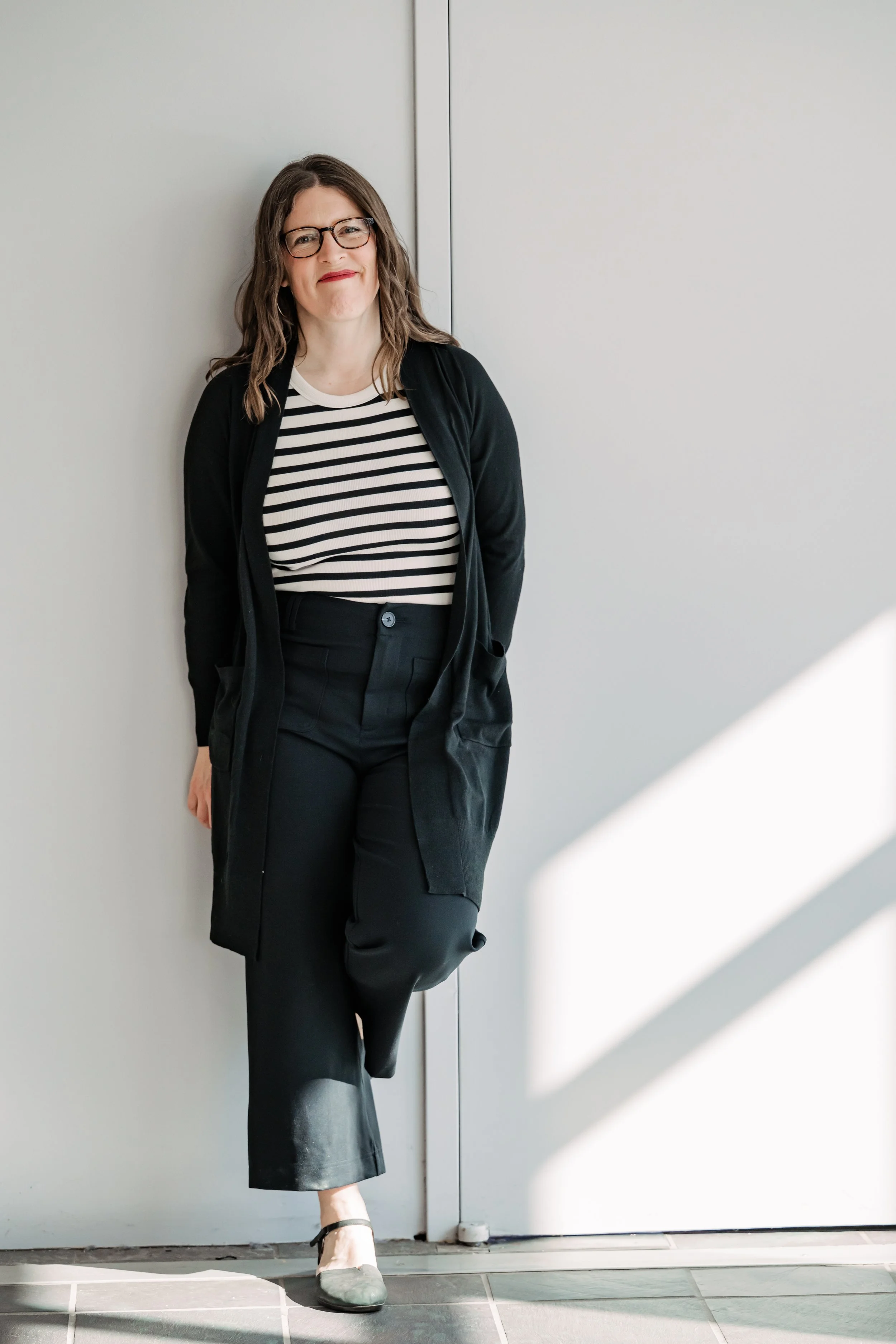 Sarah Sanderson smiling and standing in front of a white wall