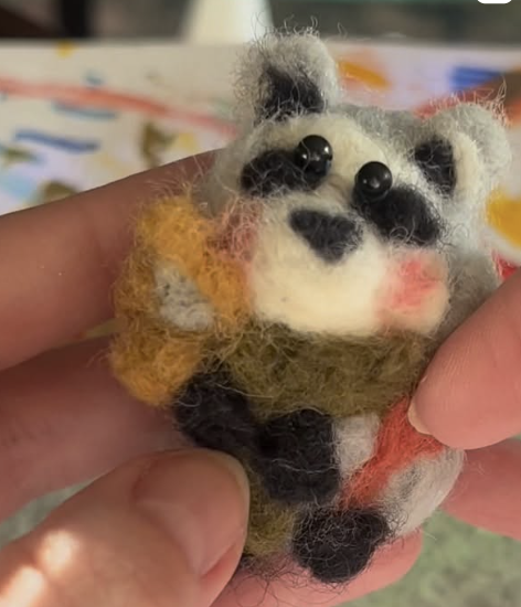 Felted panda bear holding a yellow flower