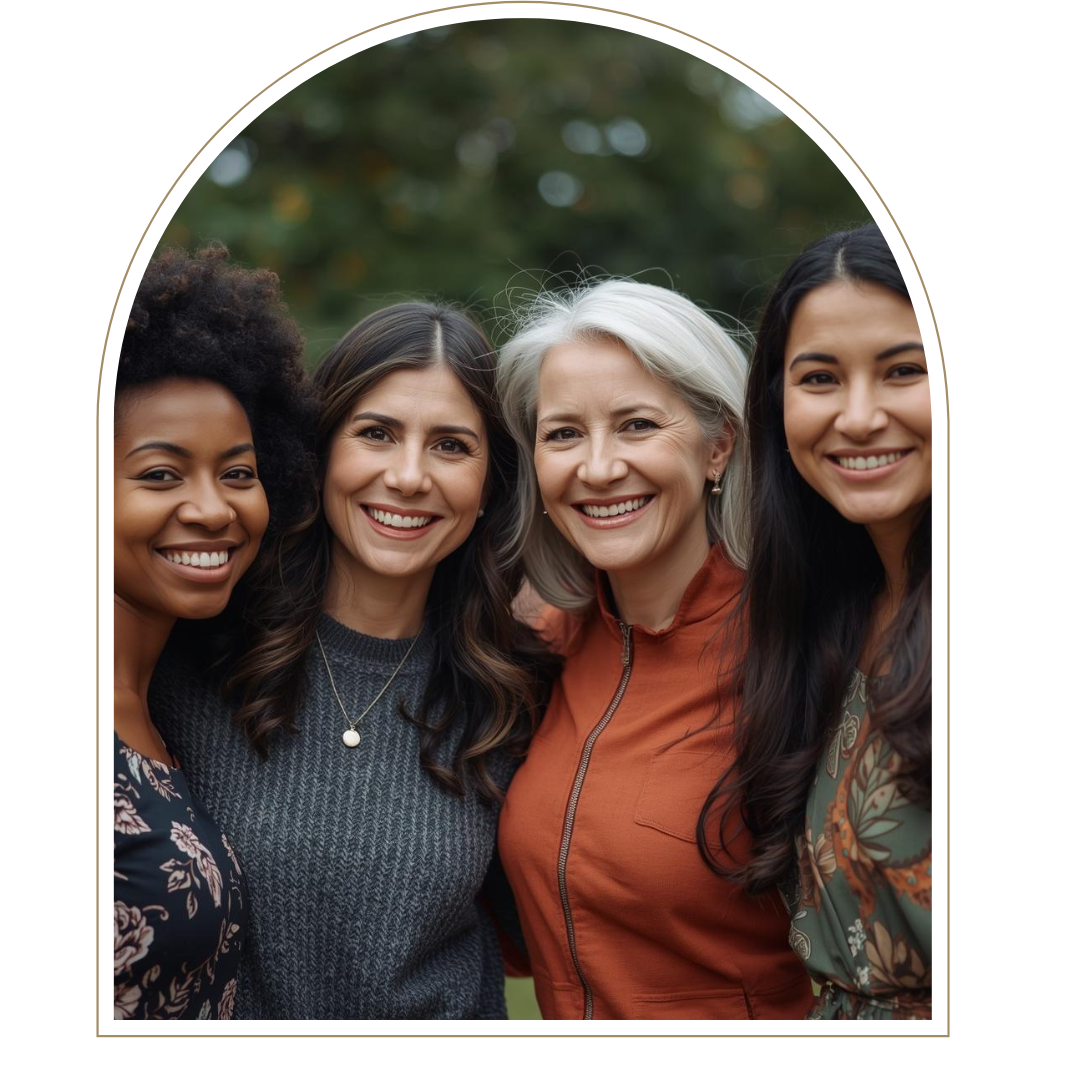 Four women smiling outdoors, standing close together, with a blurred green and brown background.