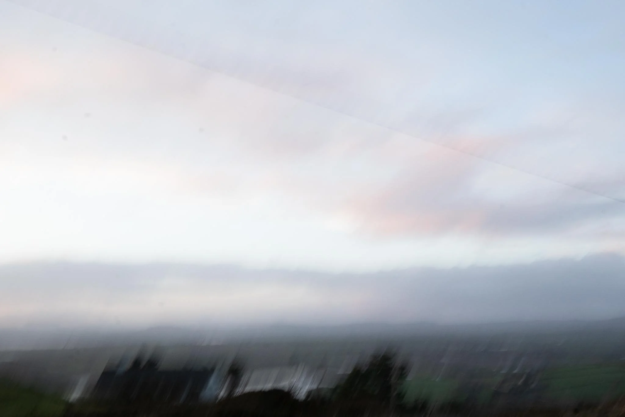 Blurred landscape scene with dark silhouettes of trees and sky with clouds, possibly during dawn or dusk. West Cork. Abstract art