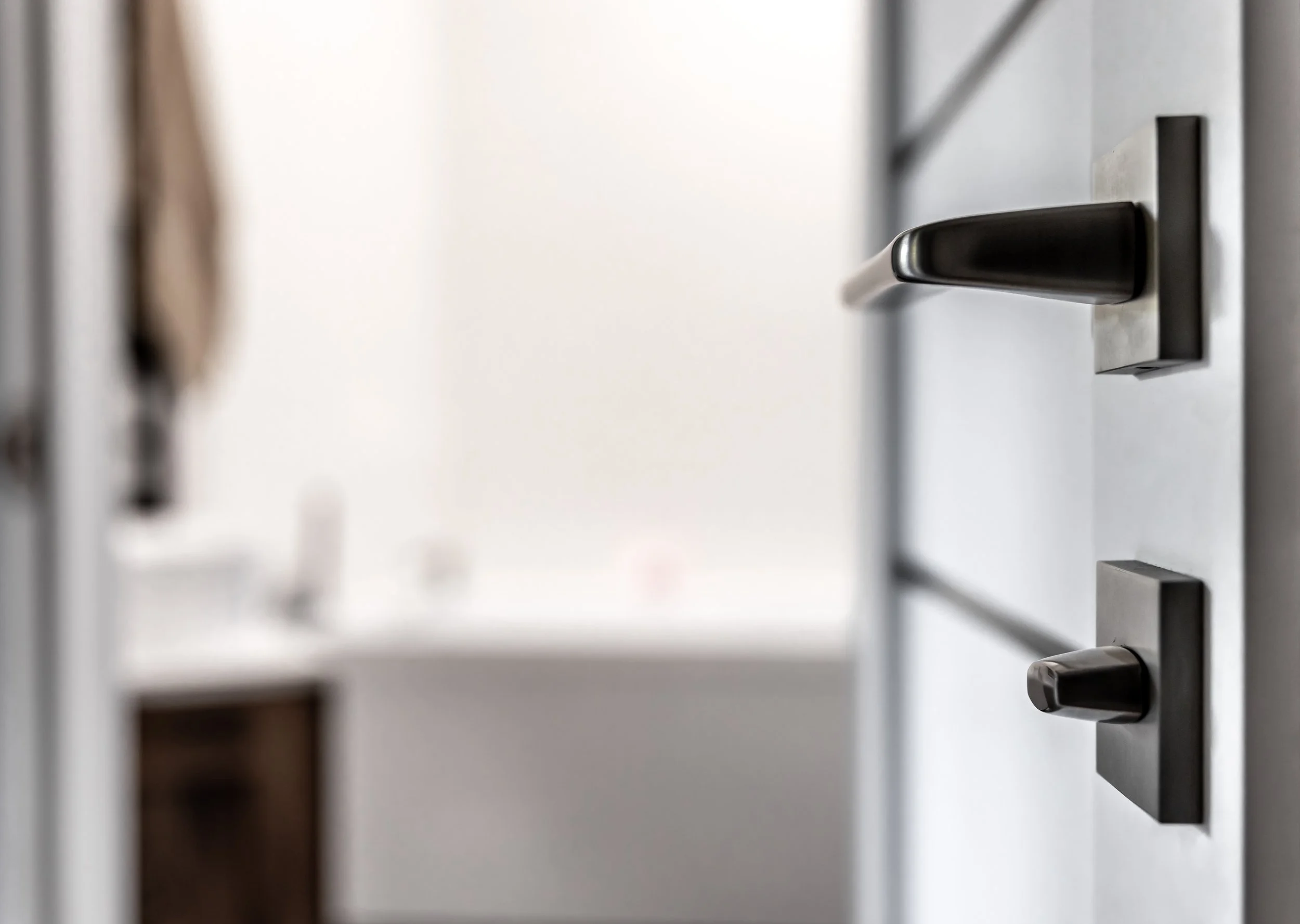 Close-up of a modern kitchen drawer handle and lock mechanism on a white cabinet.